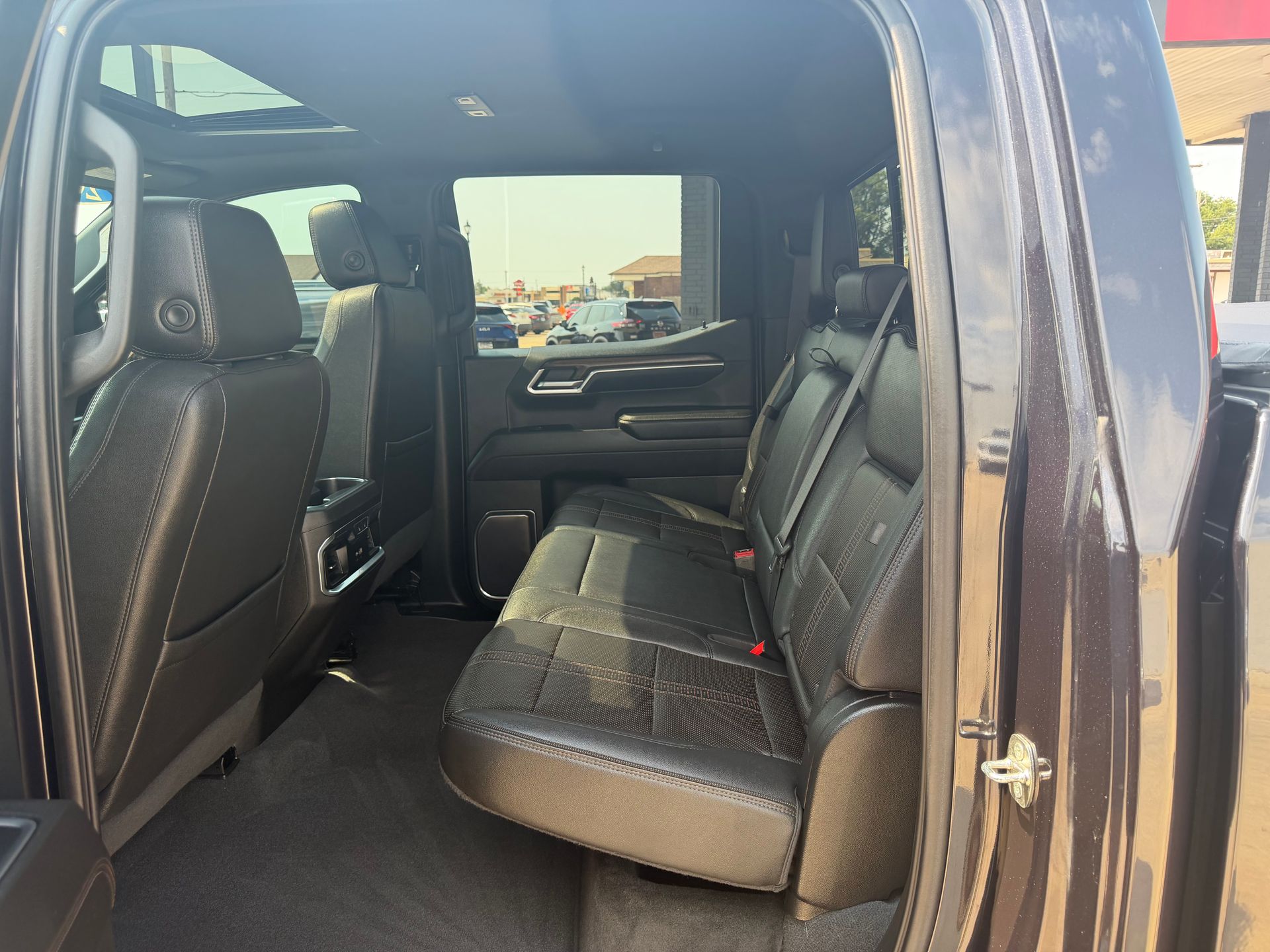 Interior of a black pickup truck, showing the rear seat area with doors open.