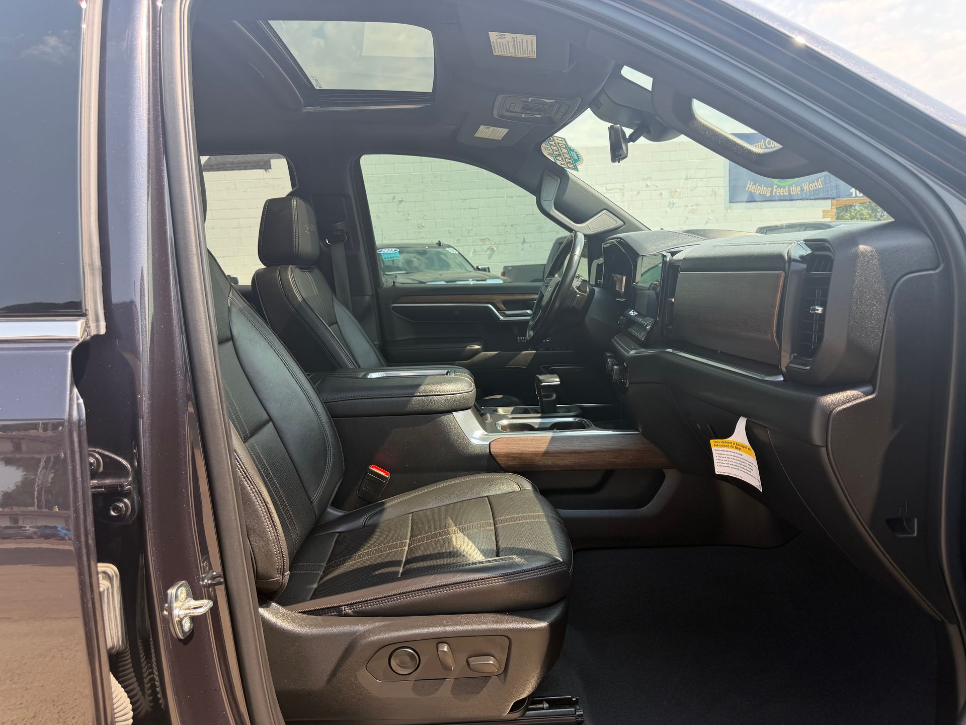 Open truck passenger-side interior with black leather seats and dashboard visible through the open door