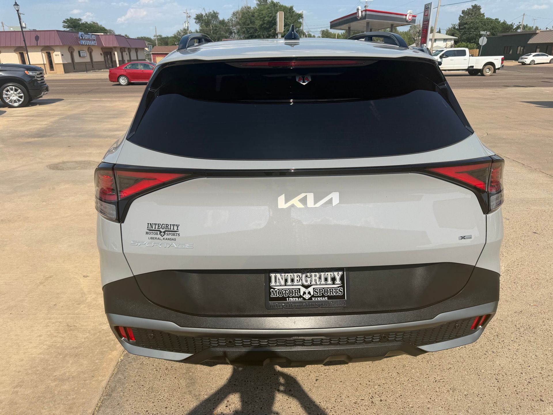Rear view of a white Kia SUV parked in a lot on a sunny day