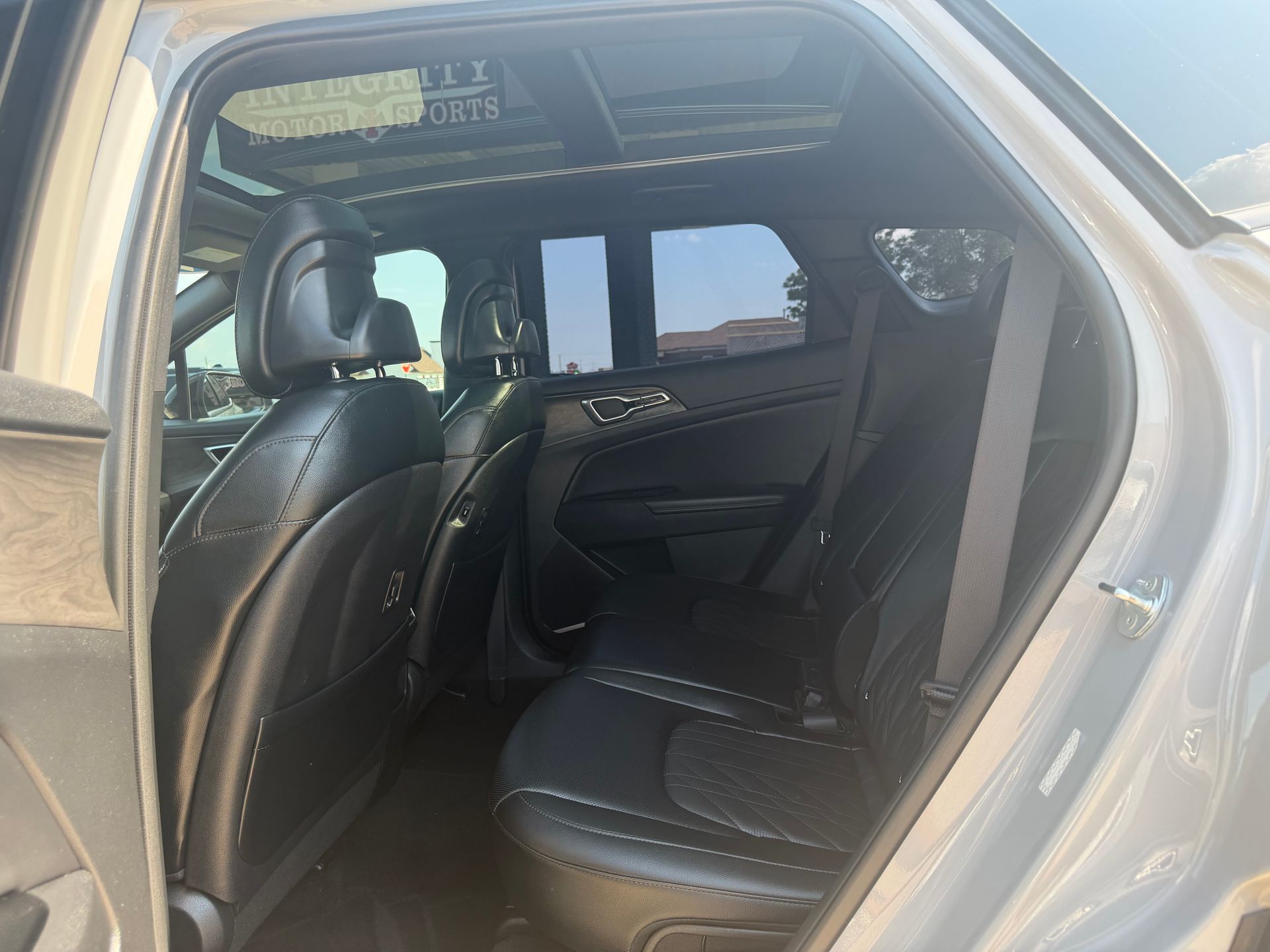 Open car rear door showing black leather back seat and interior on a silver vehicle
