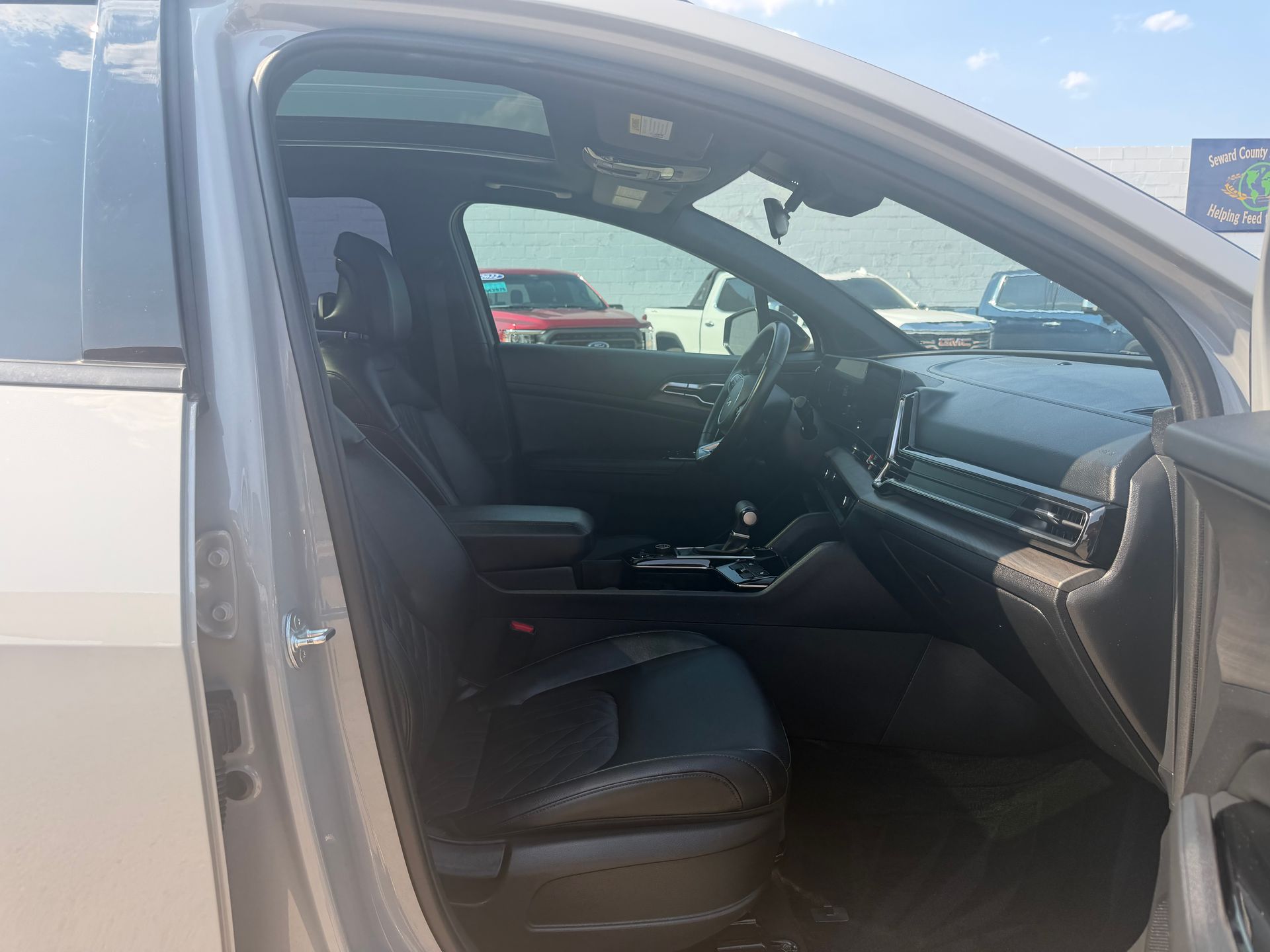 Open car door showing a black interior and front passenger seat in a silver vehicle.