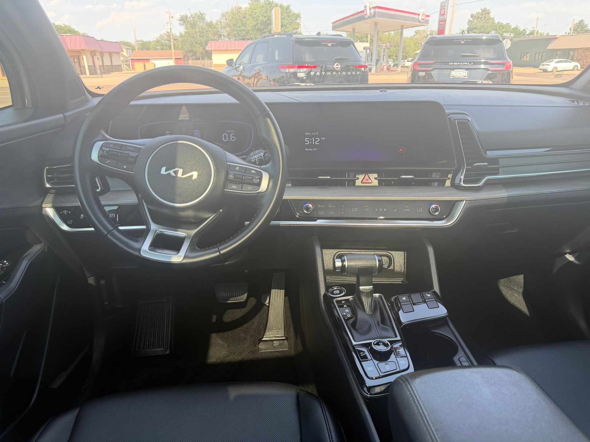 Car interior with digital dashboard, steering wheel, and center console, viewed from the driver’s seat.