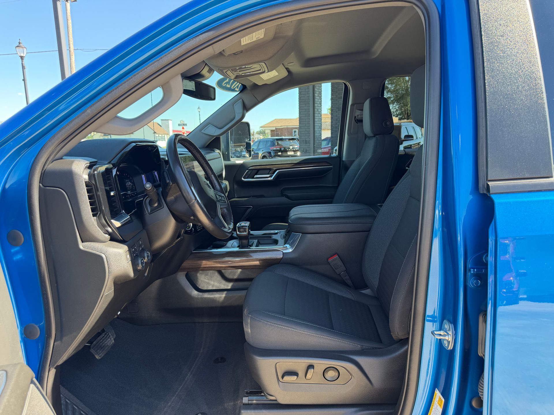 Open driver-side door of a blue pickup, showing black interior and front seat.