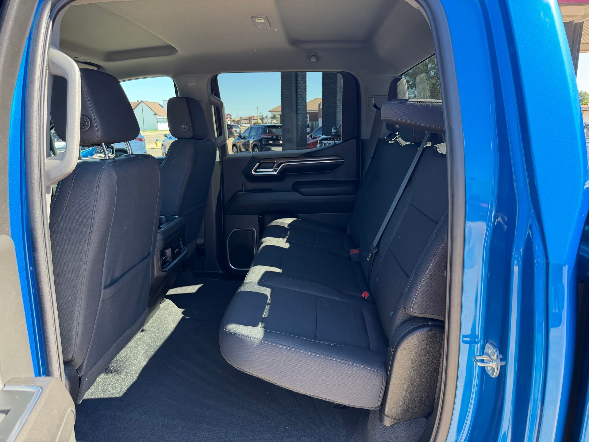 Blue van interior with a black bench seat and open side door, showing the cabin from the rear.