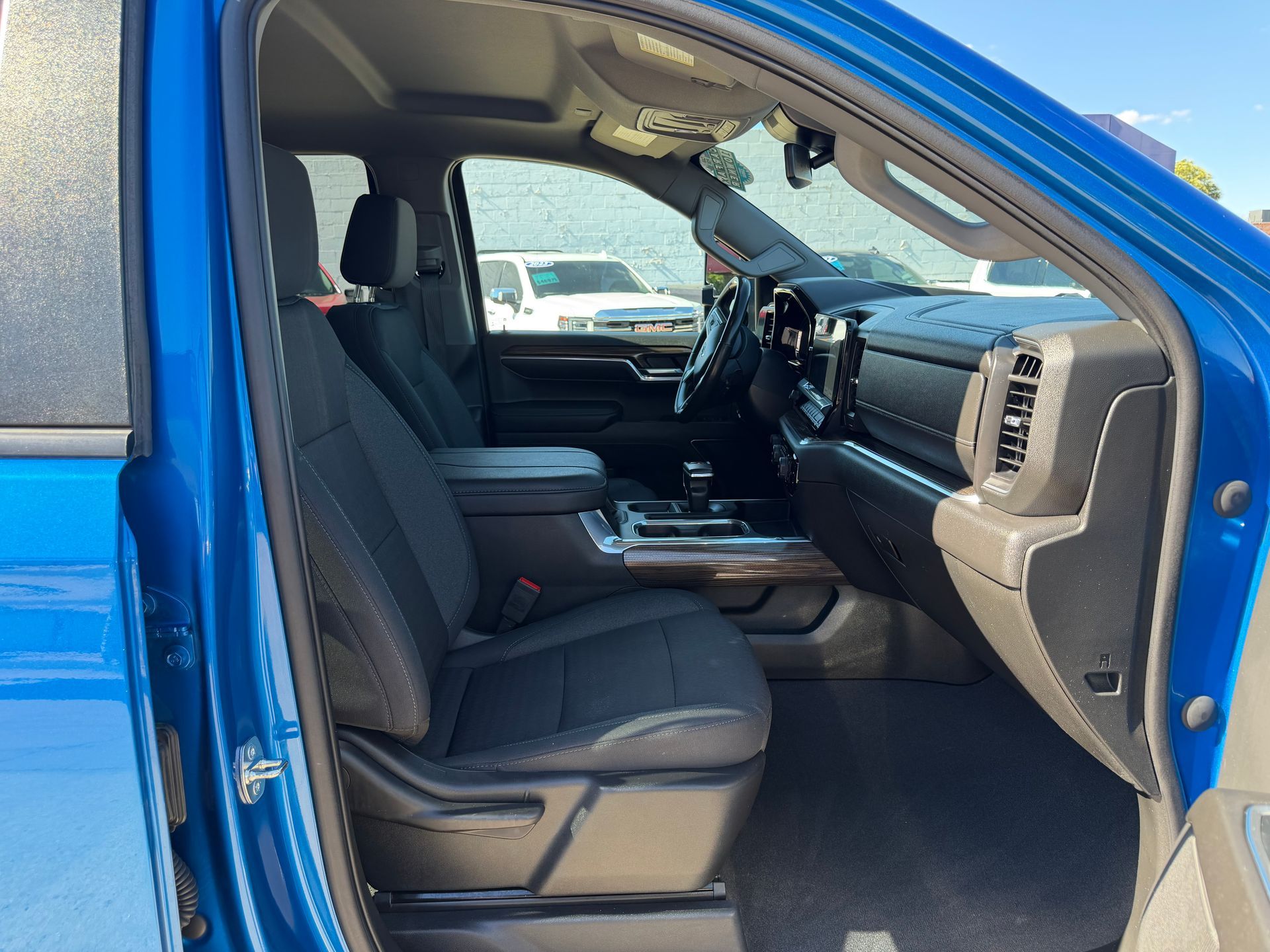 Blue truck interior with open driver door, black seats, and dashboard visible