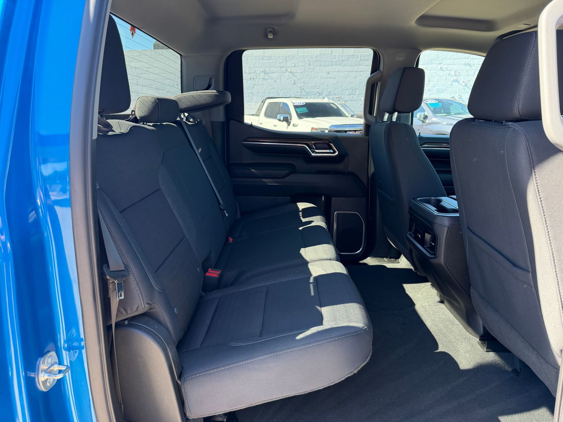 Blue pickup truck interior with dark cloth rear seats and open rear door, showing a bright cab interior
