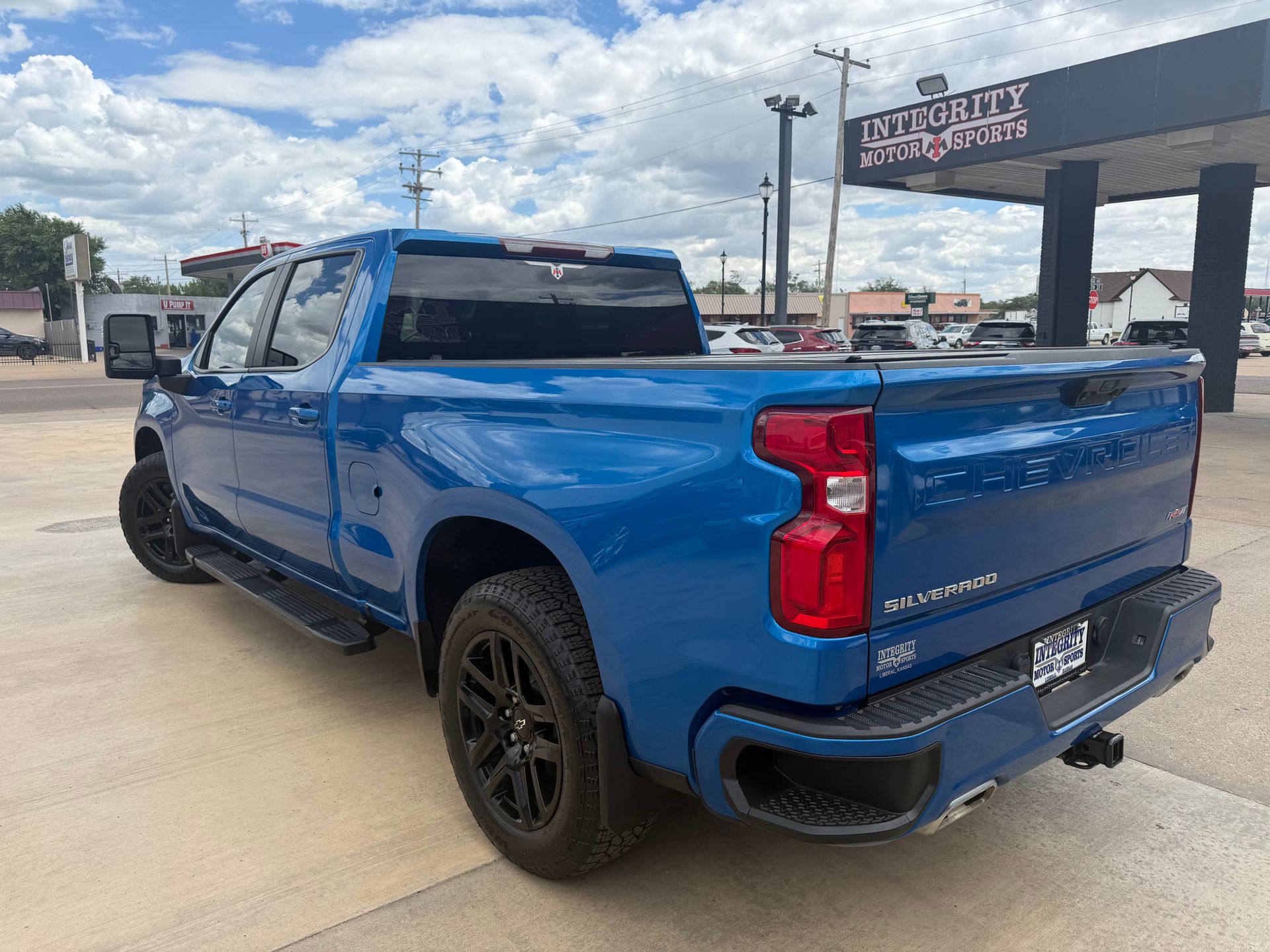 Blue Chevrolet pickup truck parked outdoors at a dealership, rear three-quarter view
