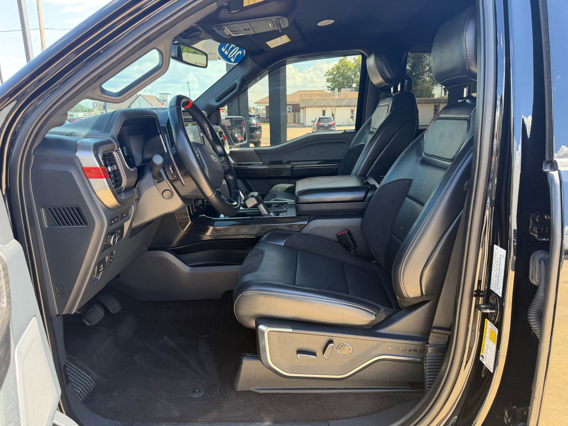Black truck interior with open driver’s door, leather seats, and steering wheel visible