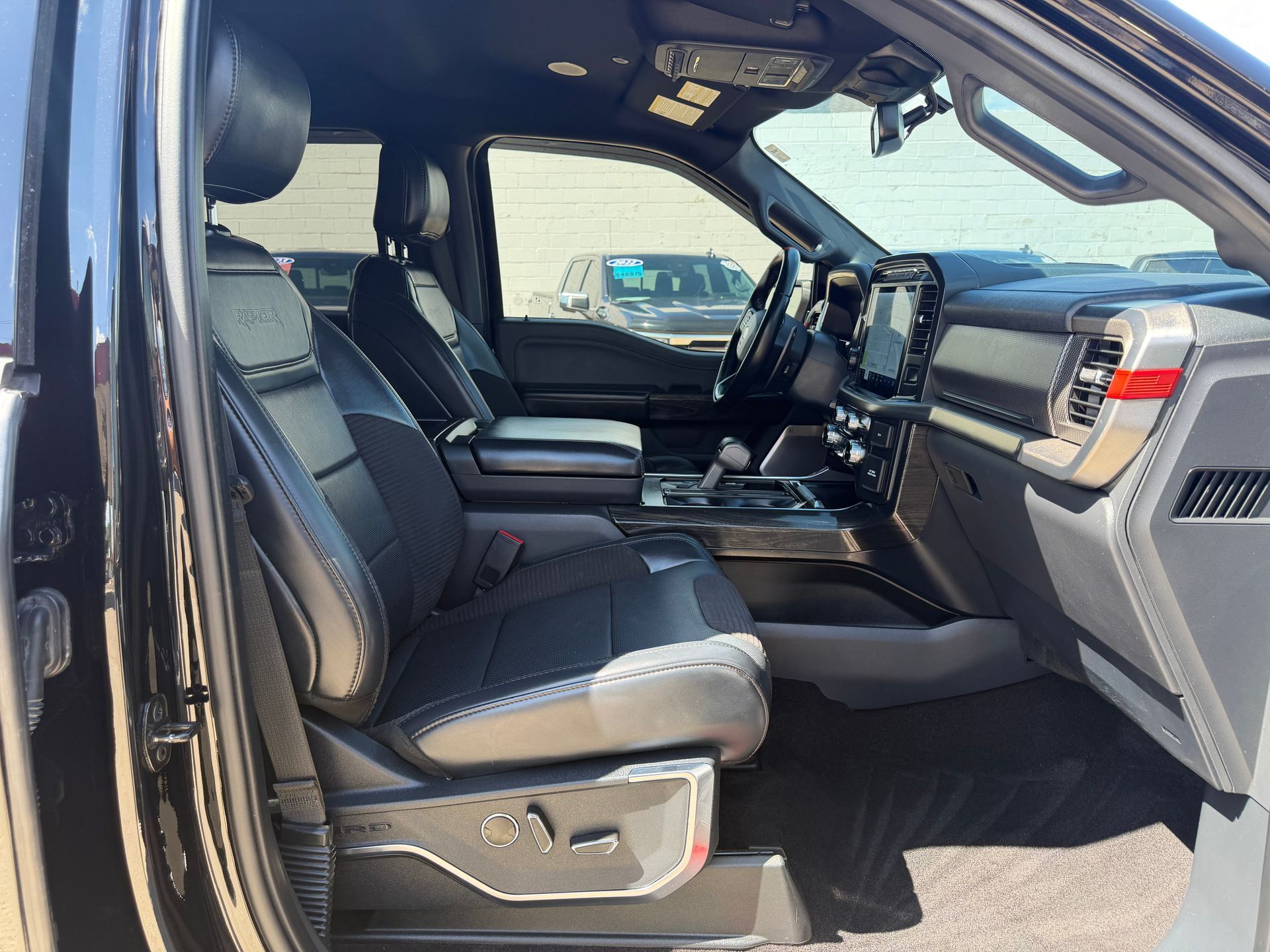Black leather truck cabin with open door, showing front seats and dashboard from the passenger side.