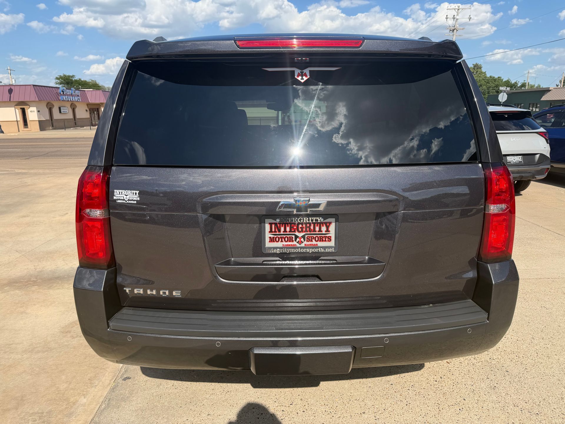 Rear view of a gray SUV parked outdoors under a sunny sky