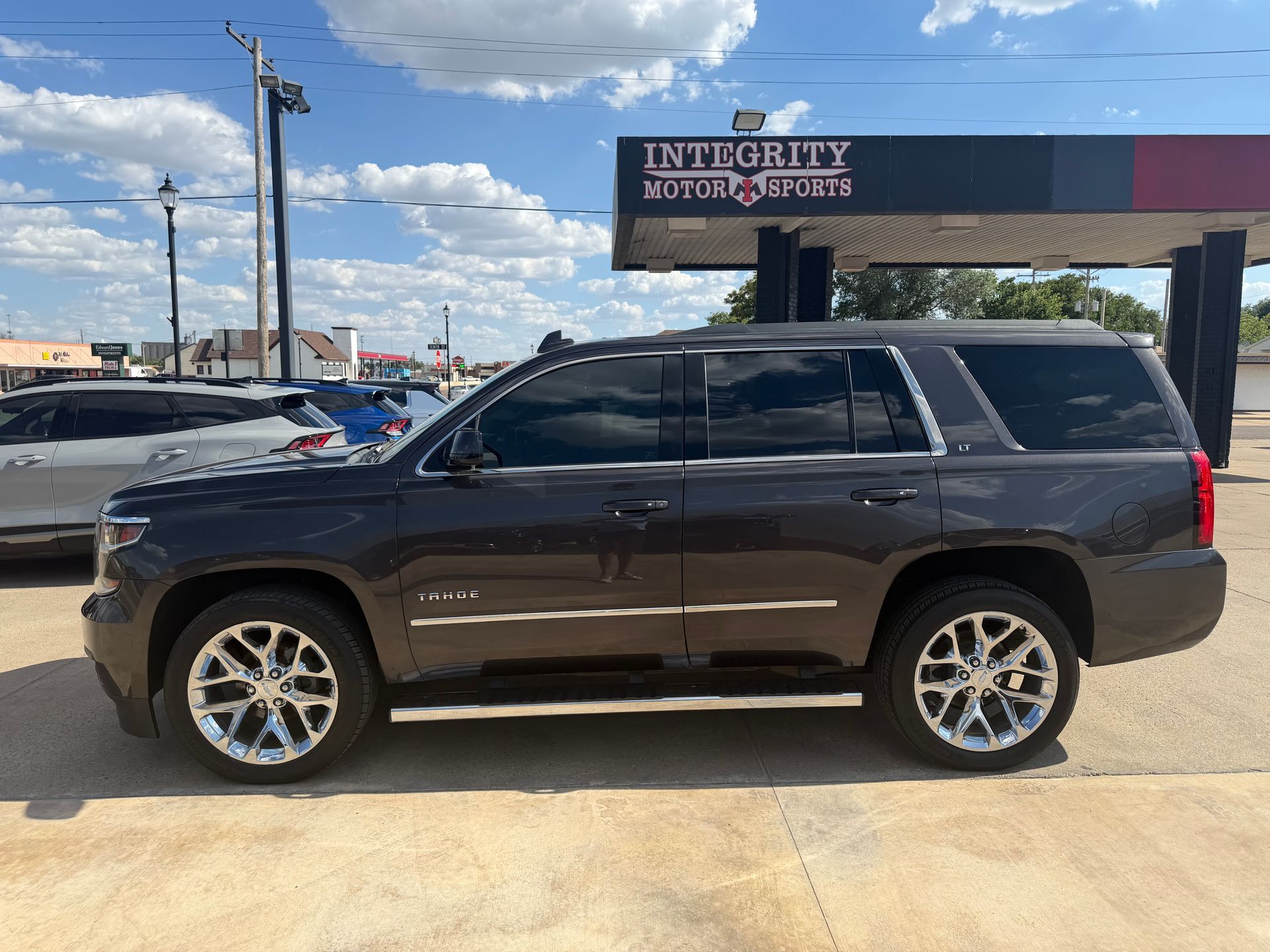 Black SUV parked outside an Enterprise Rent-A-Car lot under a partly cloudy sky