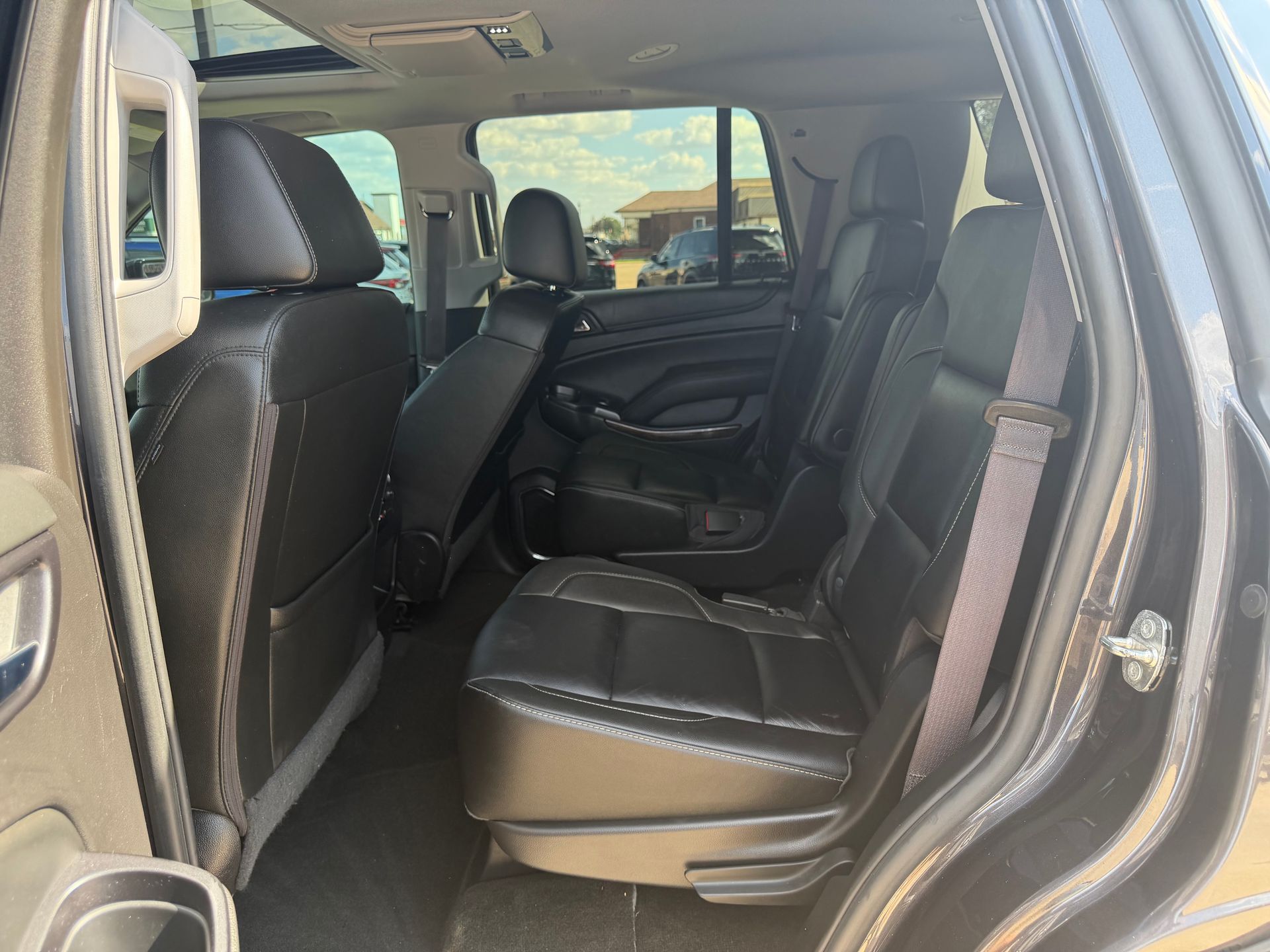 Interior of a black SUV with folded seats, showing the rear passenger area and open door.