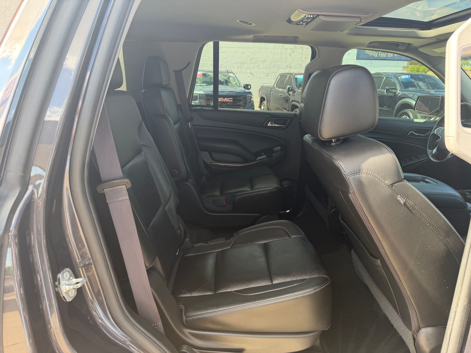 Open SUV rear seat interior with black leather seats and doors open.