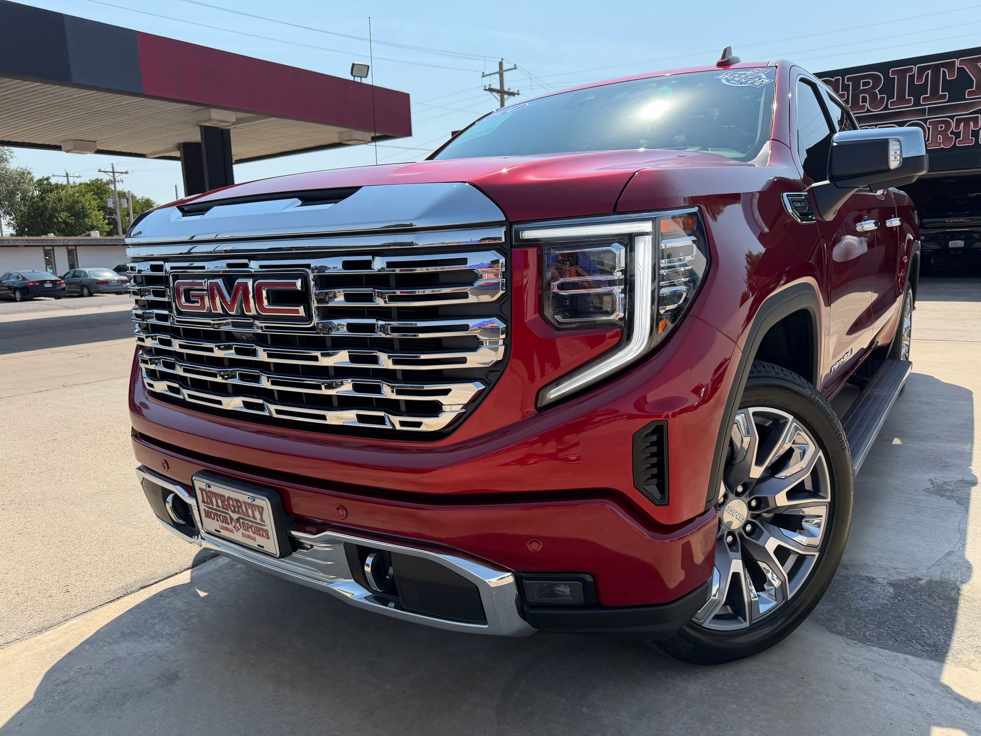 Black Chevrolet Silverado truck in front of a dealership with chrome accents and bright headlights.