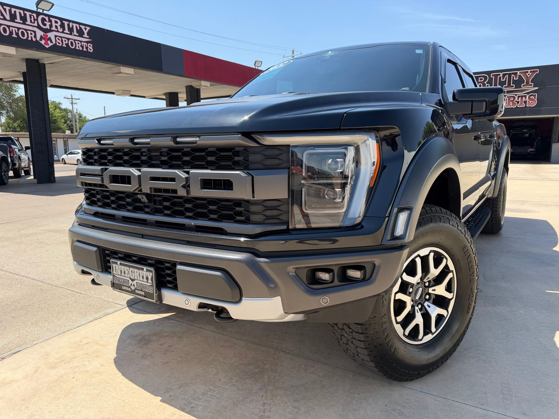 Black Chevrolet Silverado truck in front of a dealership with chrome accents and bright headlights.