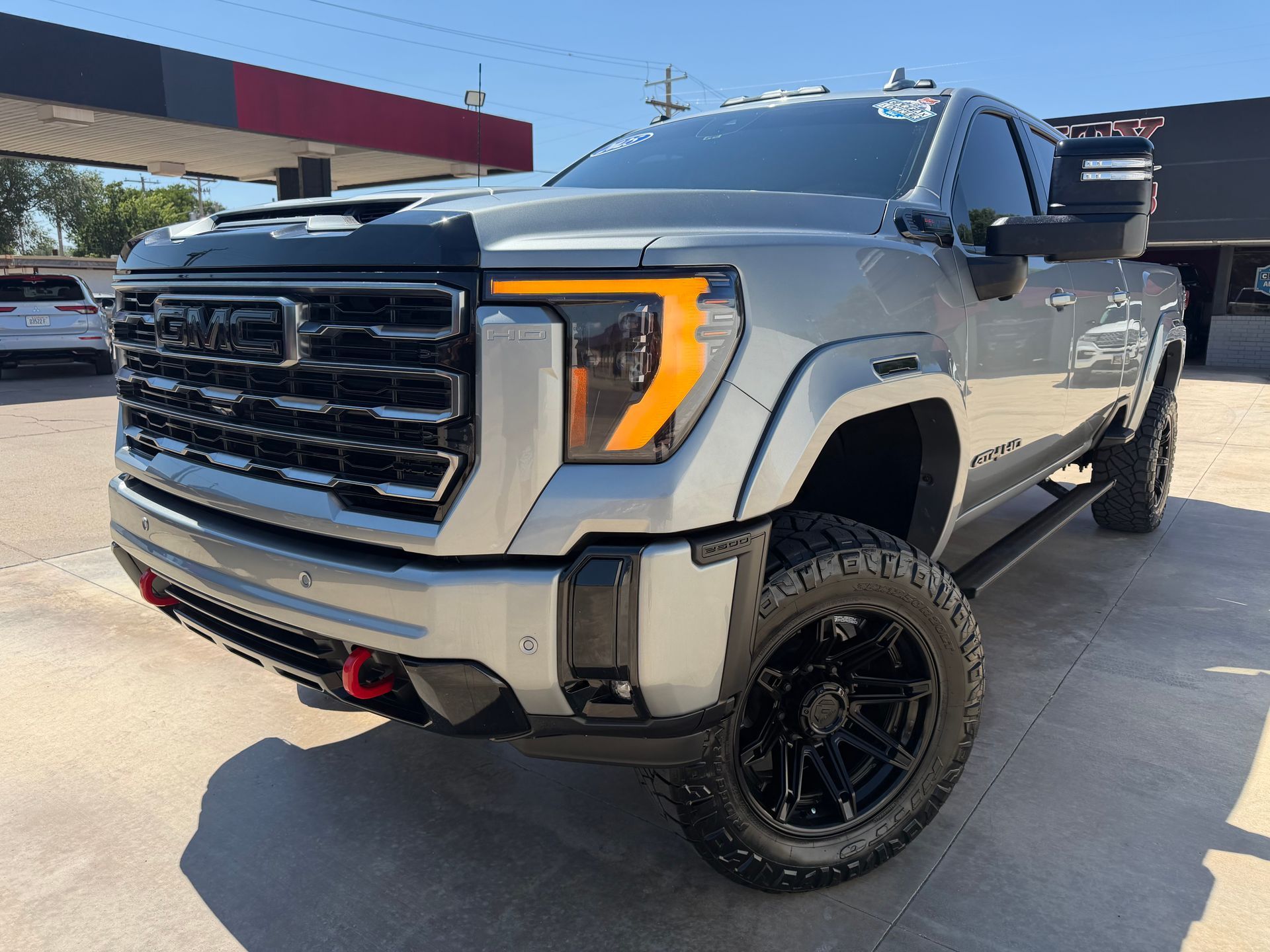 Black Chevrolet Silverado truck in front of a dealership with chrome accents and bright headlights.