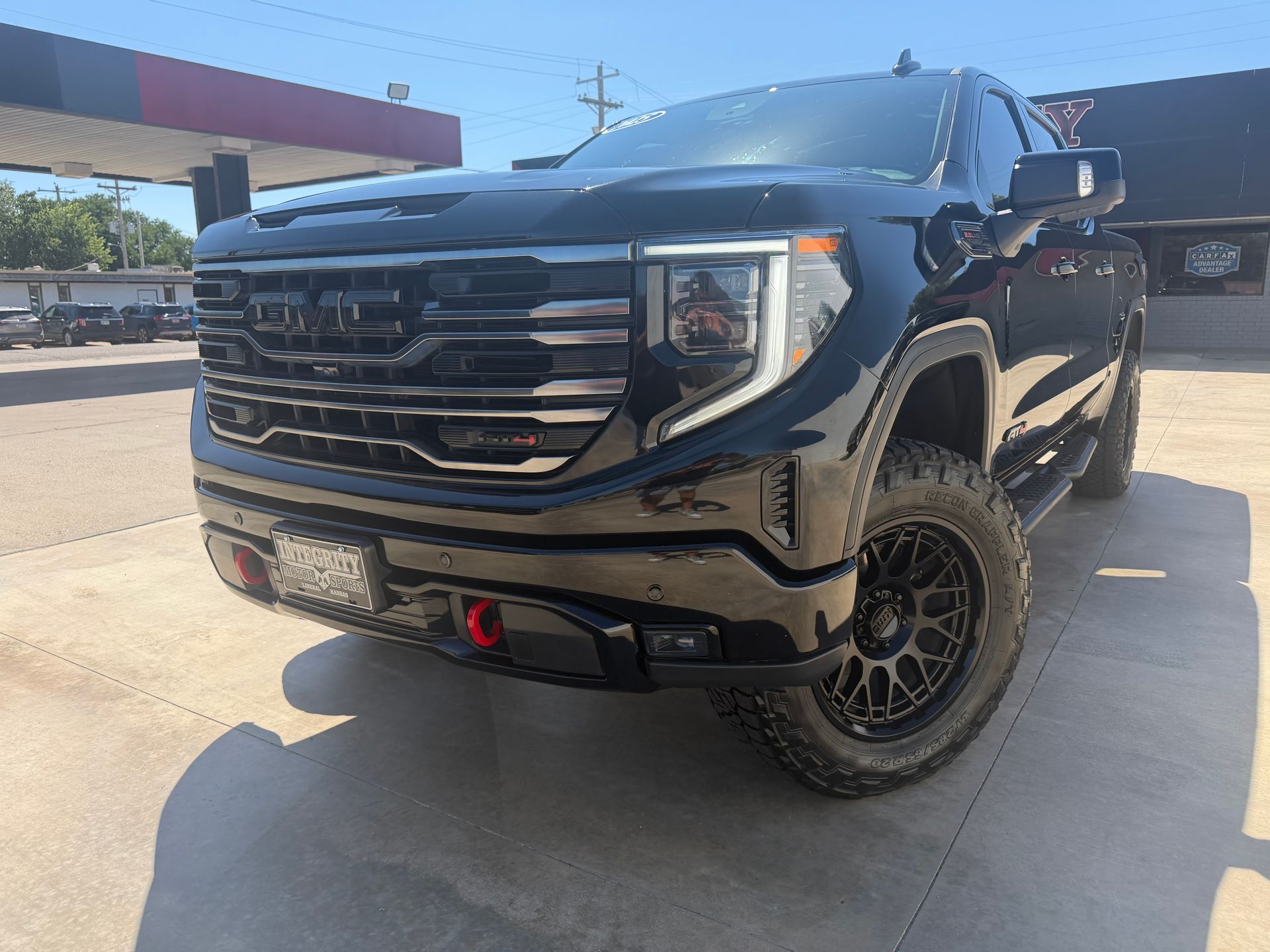 Black Chevrolet Silverado truck in front of a dealership with chrome accents and bright headlights.