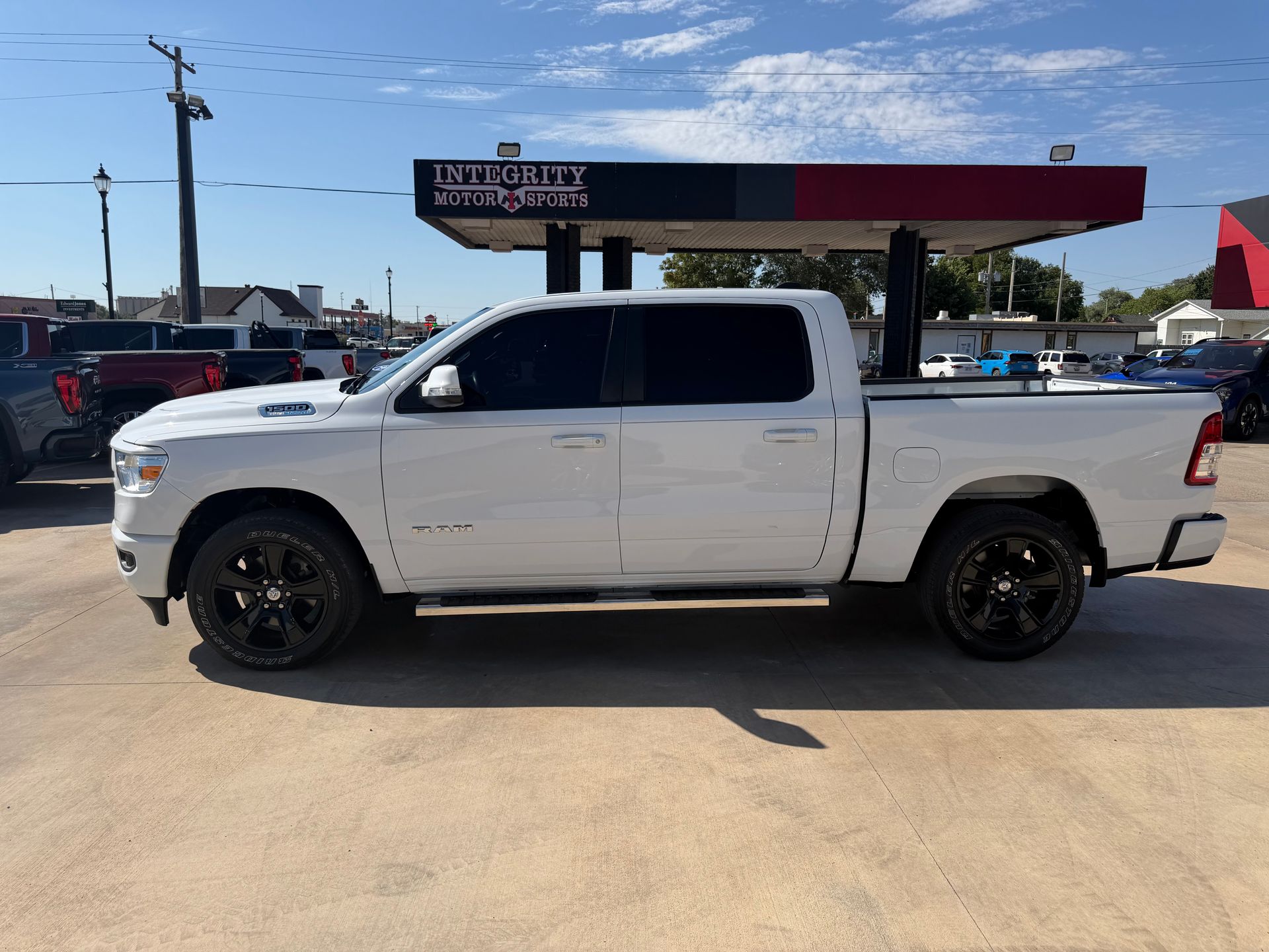 White lifted pickup truck parked at a gas station under a sunny blue sky