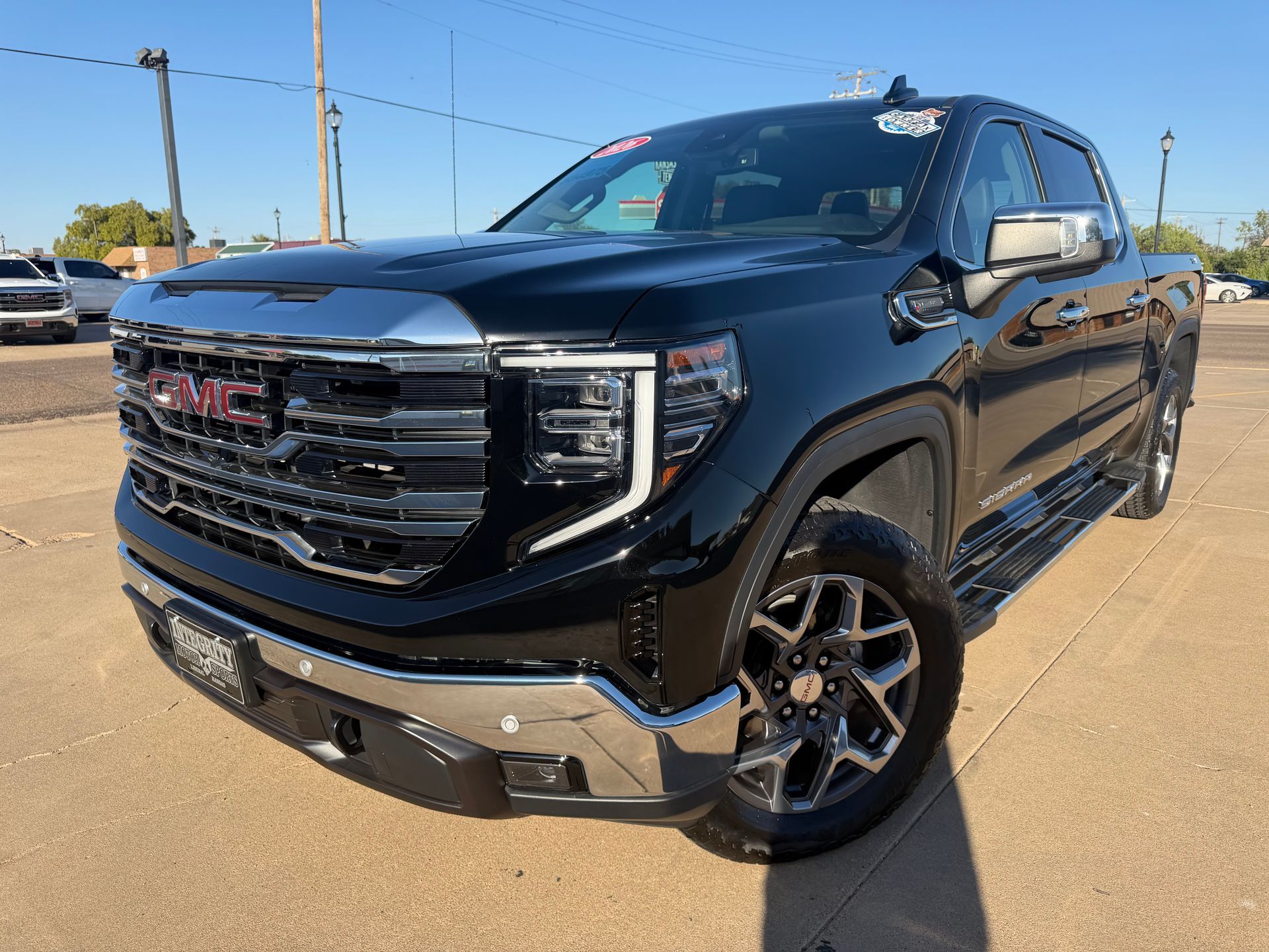 Black Chevrolet Silverado truck in front of a dealership with chrome accents and bright headlights.