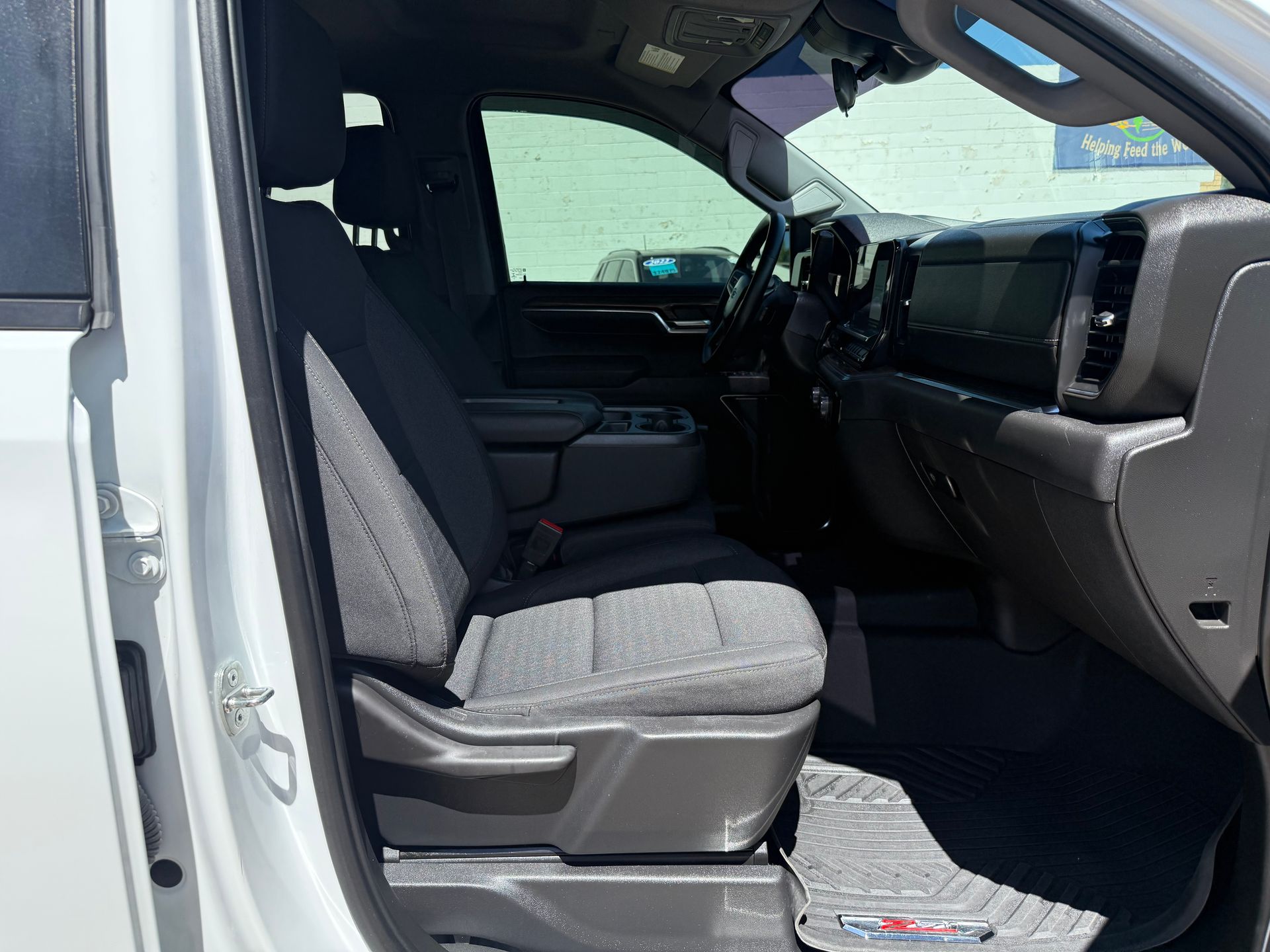 White truck interior: black seats, dashboard, steering wheel, and rubber floor mat.