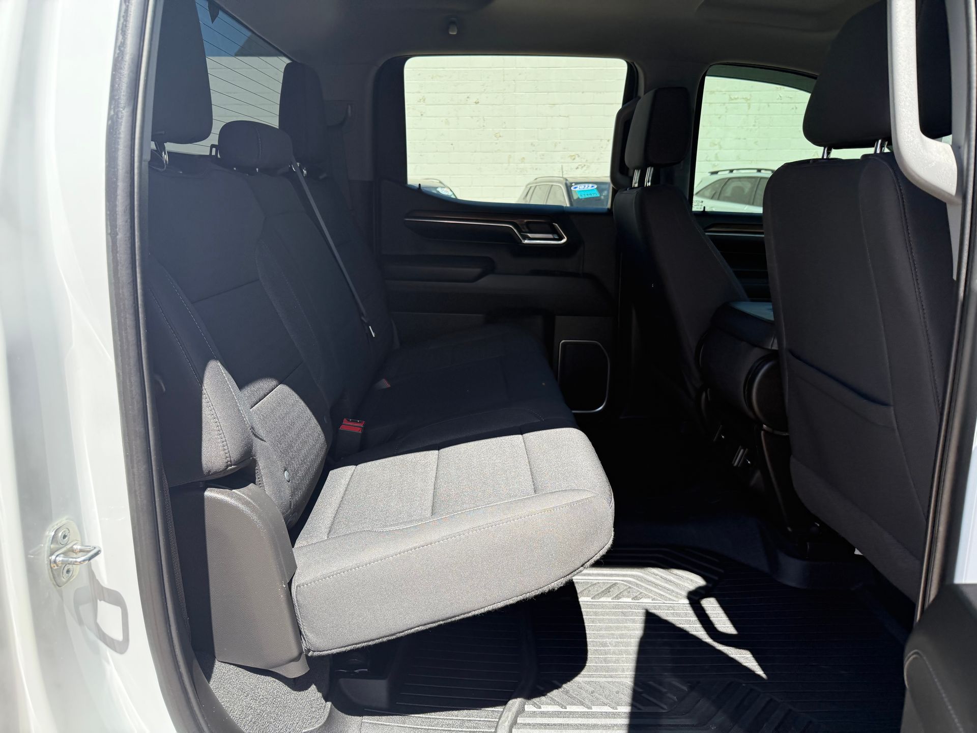 Interior rear seats of a white pickup truck, showing black cloth seats and floor mats.