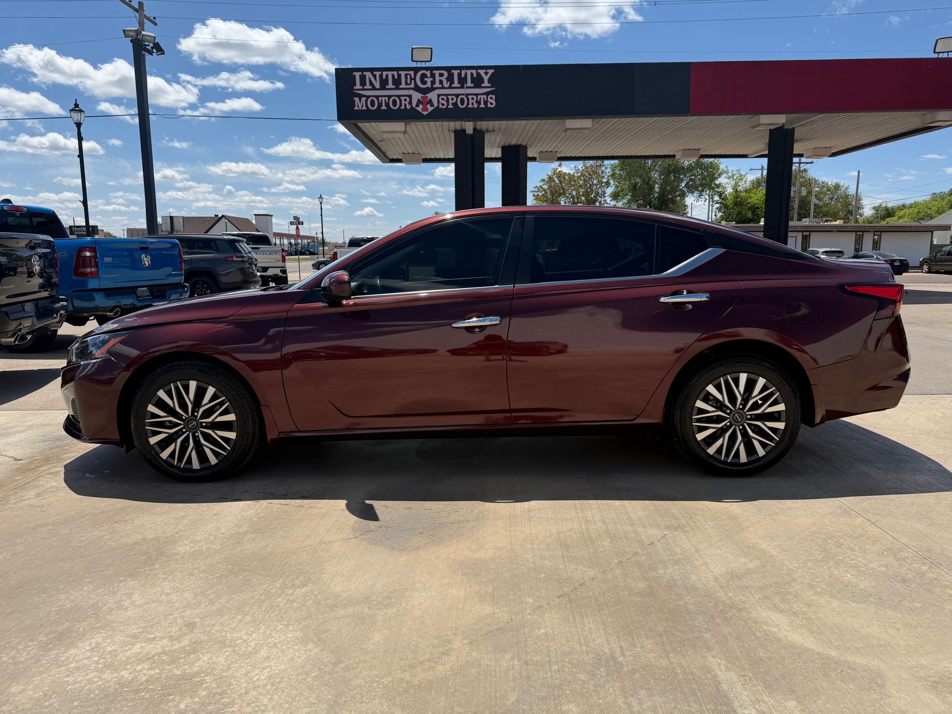 A maroon sedan parked in front of a gas station on a sunny day.