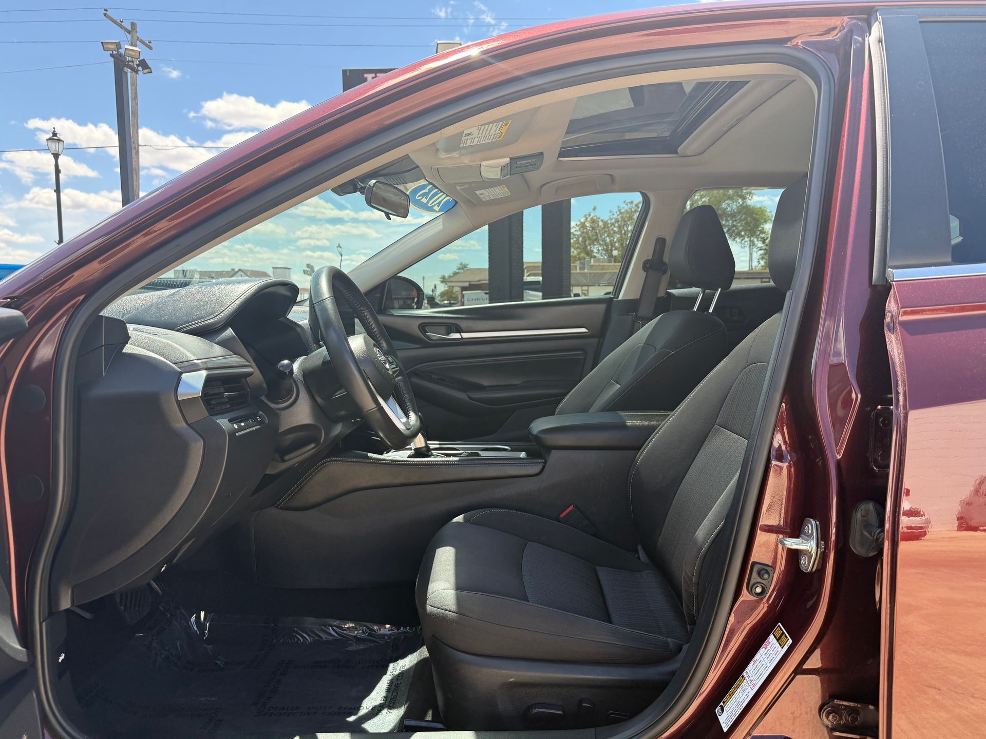 Interior view of a red car with black seats, open sunroof, and a view of the outside.