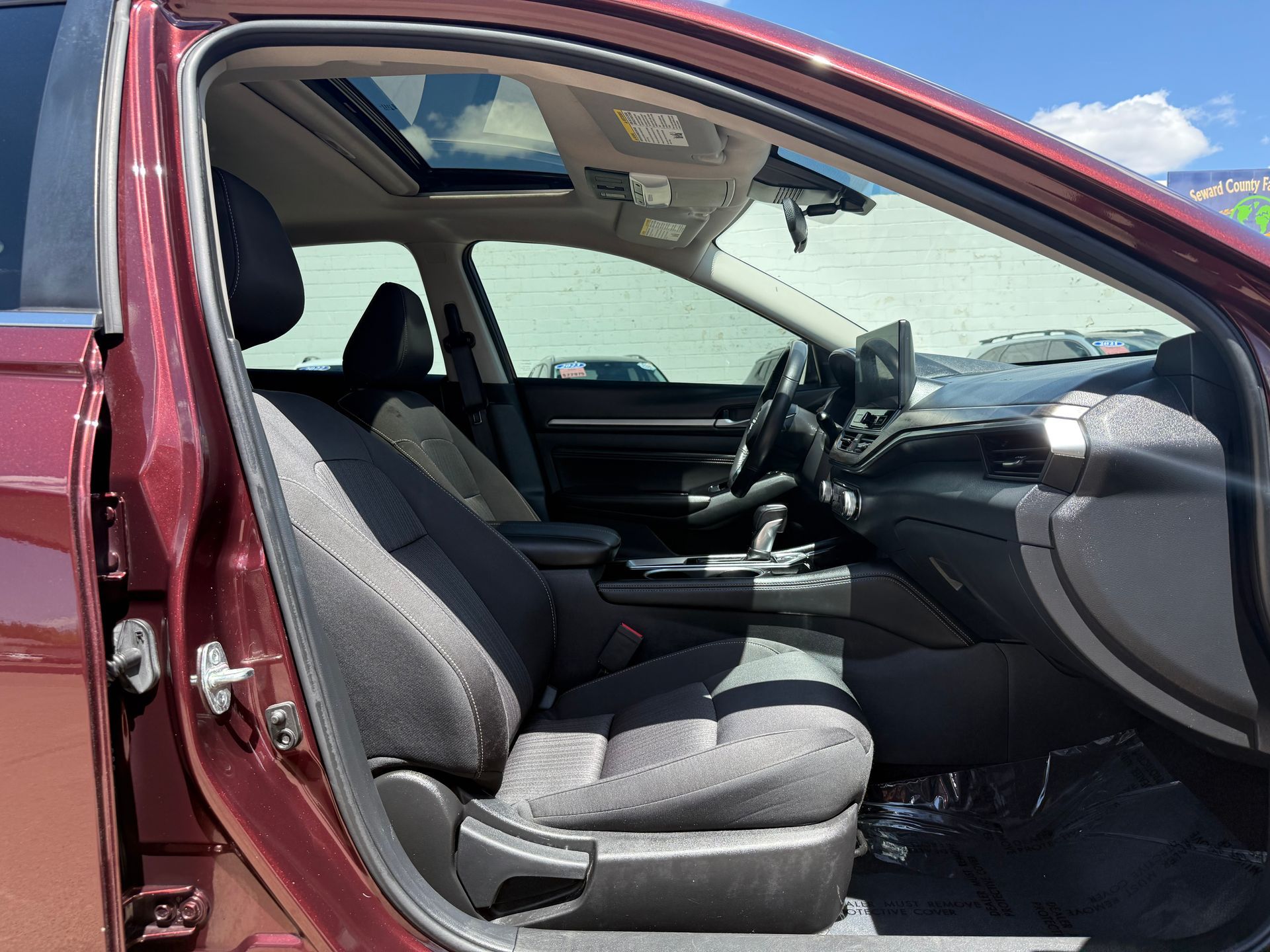 Interior of a burgundy car, showing front seats, dashboard, and sunroof.