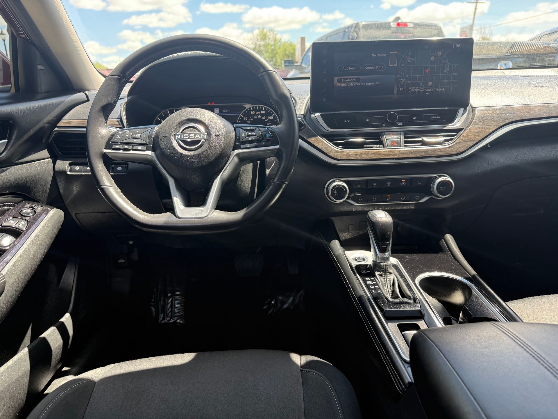 Black car interior with steering wheel, infotainment screen, and gear shift visible.