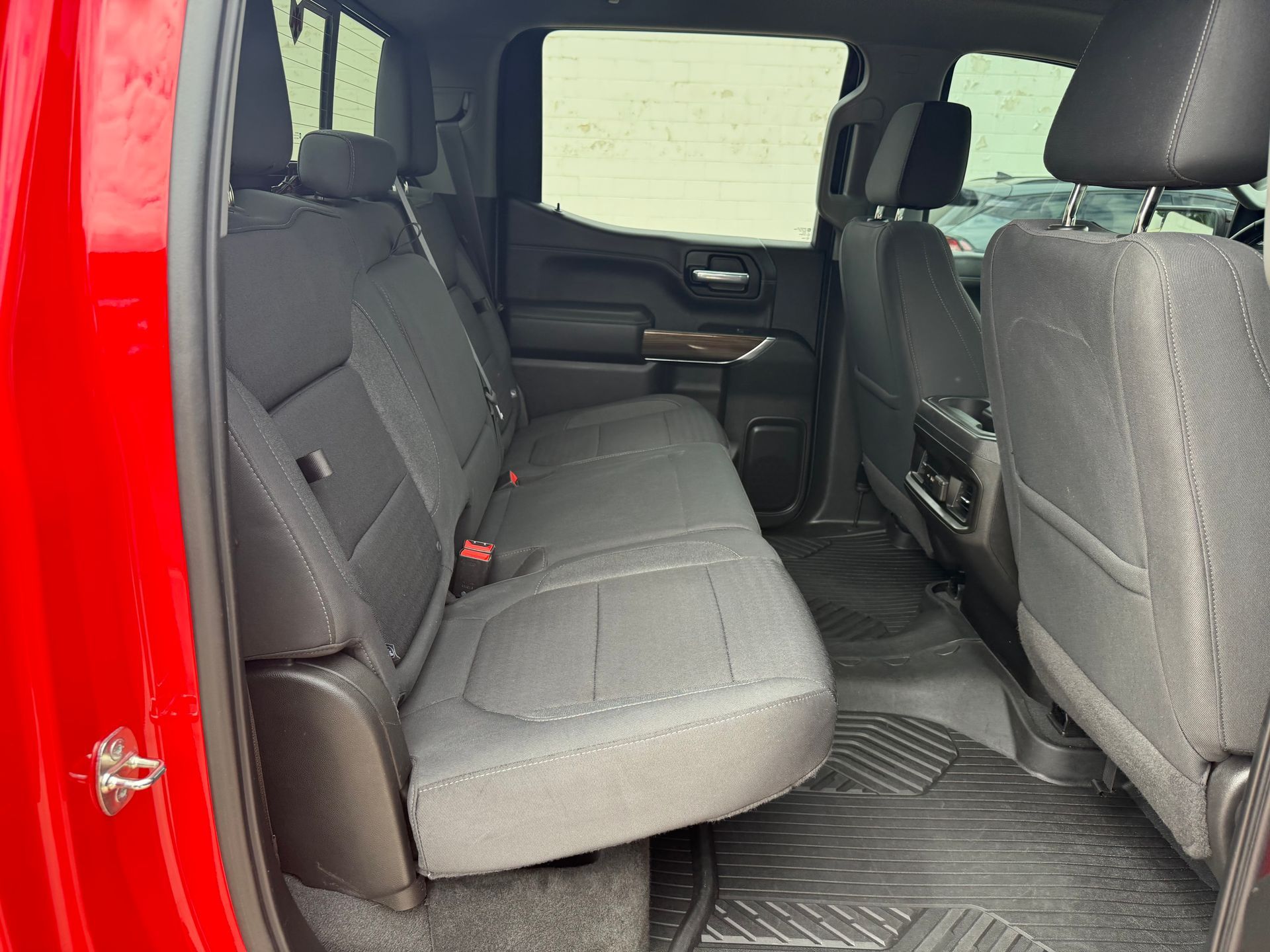 Red truck interior: back seat with gray fabric, black floor mat.