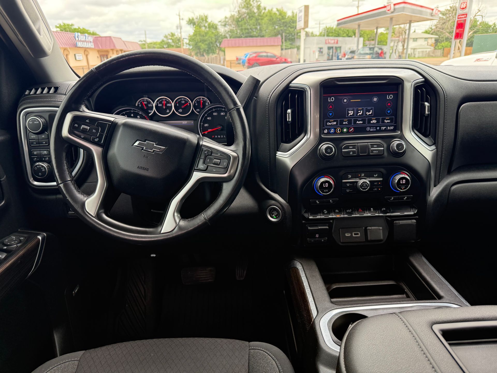 Interior of a black GMC truck; dashboard with steering wheel, infotainment screen, and center console.
