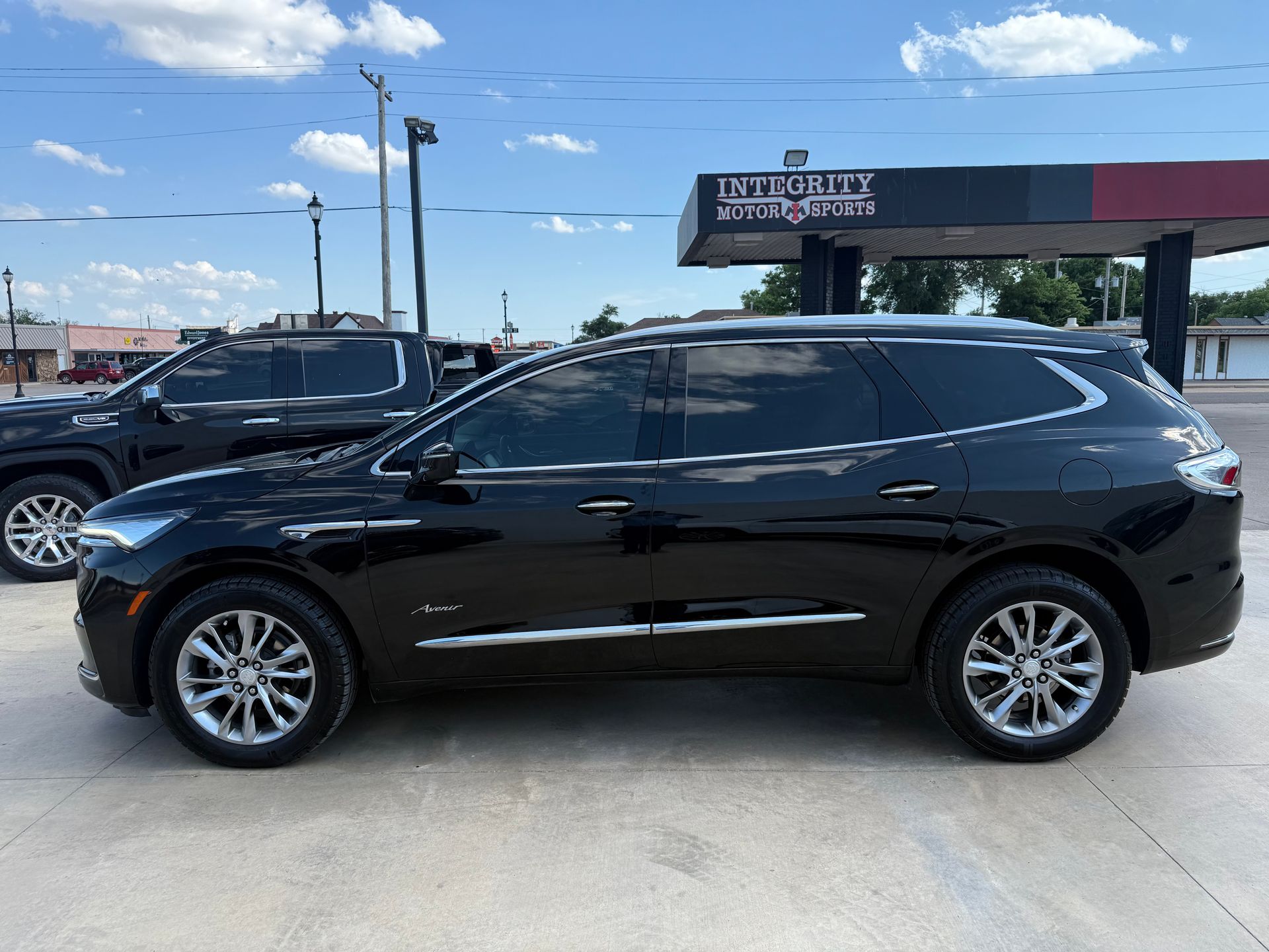 Black SUV parked outside a business with tinted windows; blue sky.