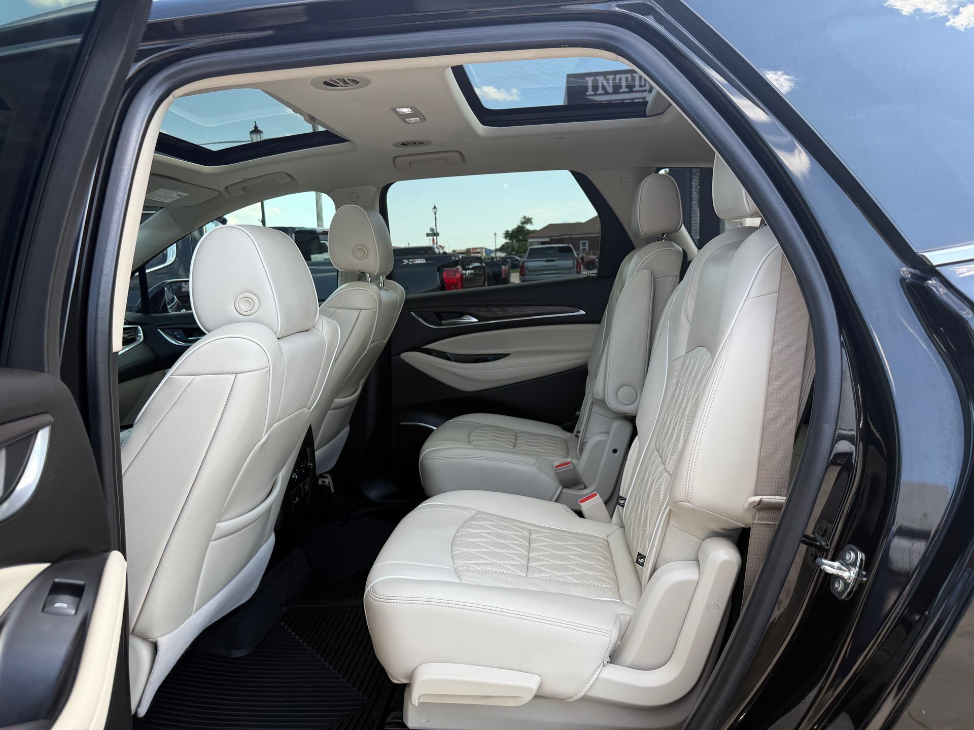 Interior view of a black SUV with beige leather seats and a sunroof.