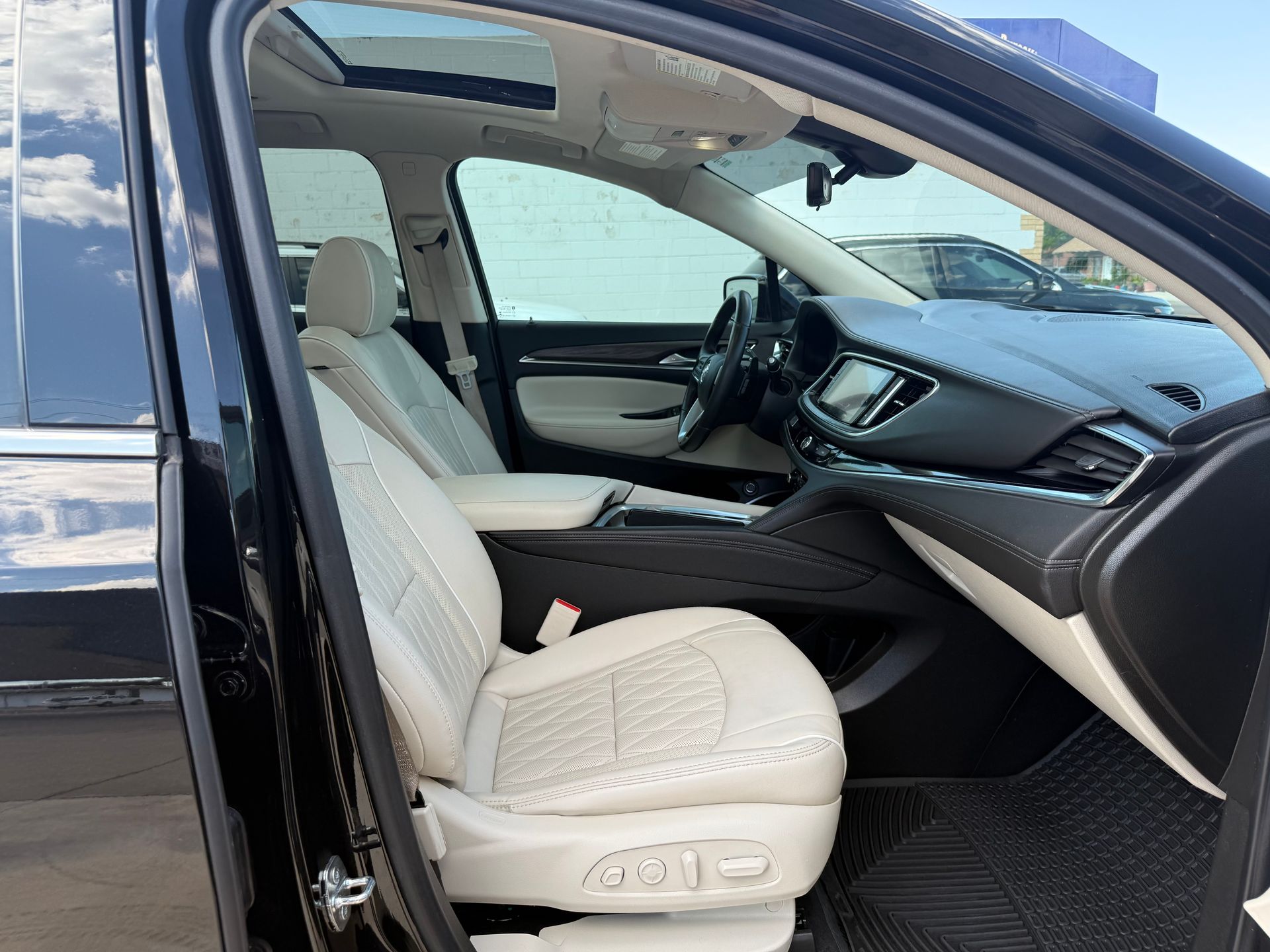Interior view of a black car with beige leather seats, a sunroof, and a black dashboard.