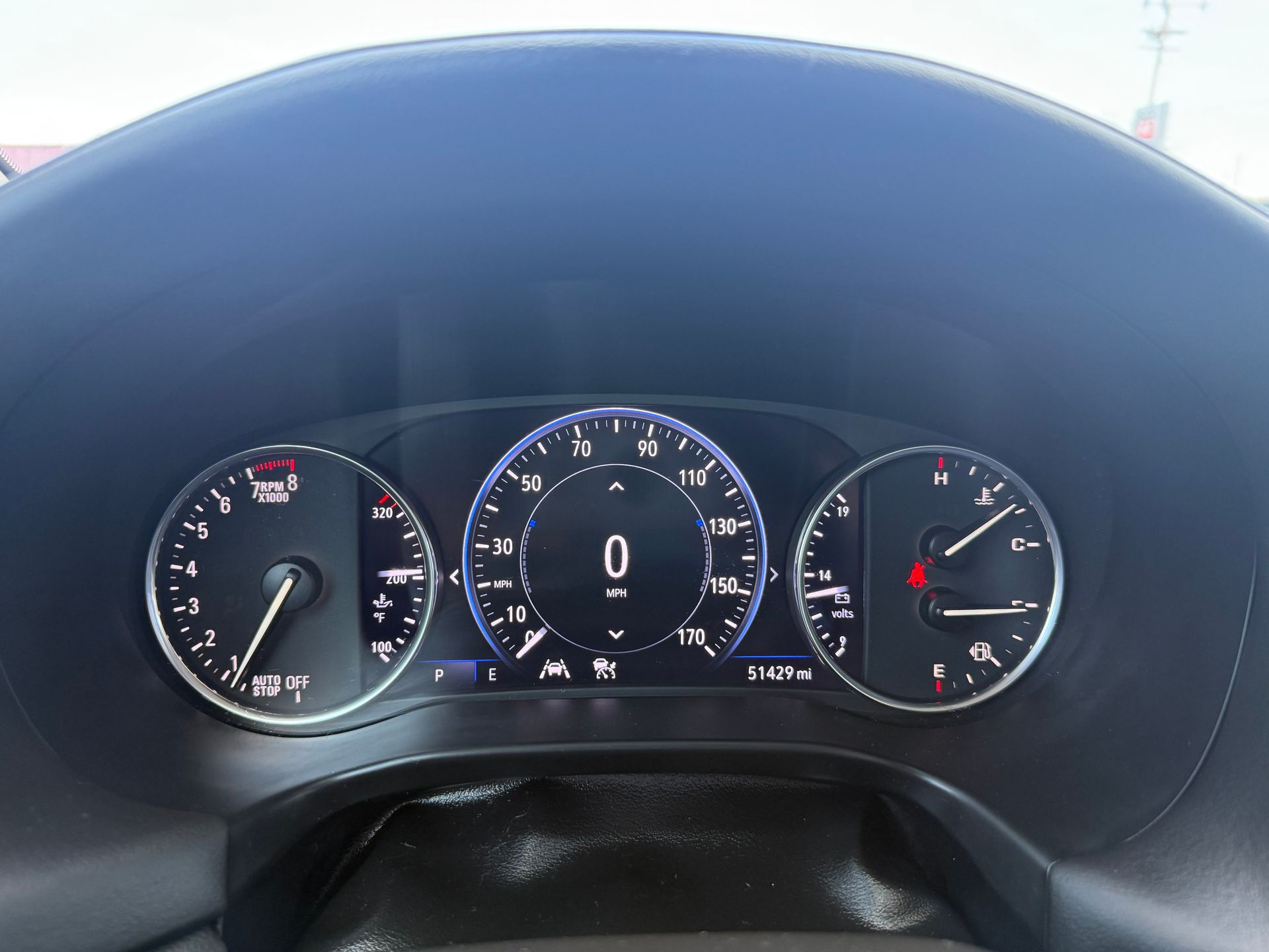 Car dashboard with speedometer at 0 mph. Gauges show various readings, and indicator lights are on.