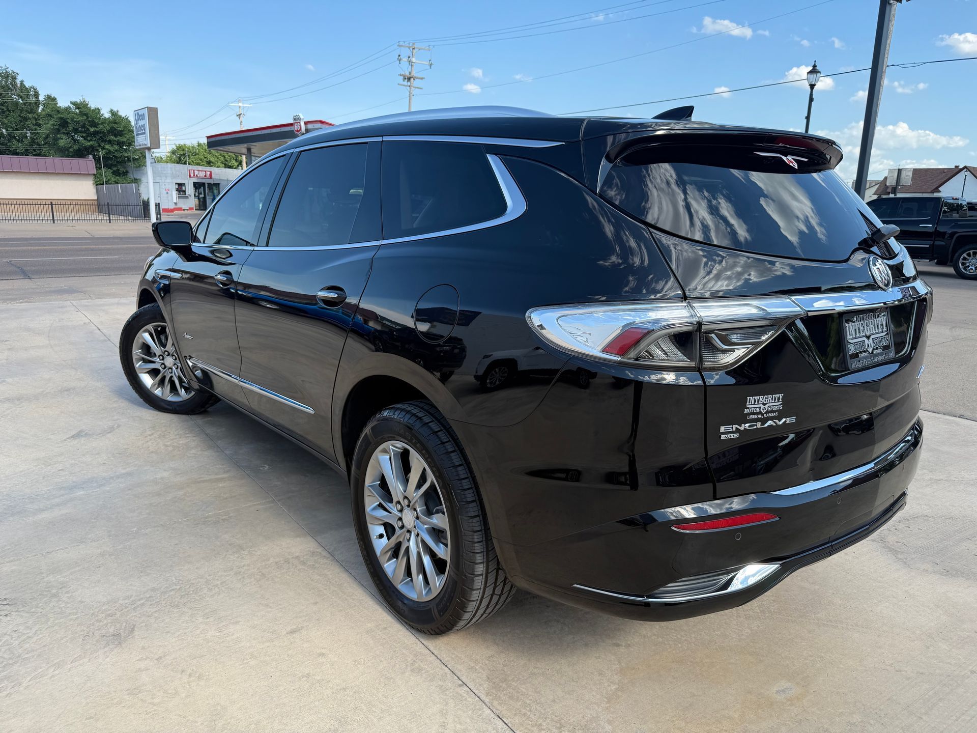 Black Buick Enclave SUV parked on a paved lot on a sunny day.