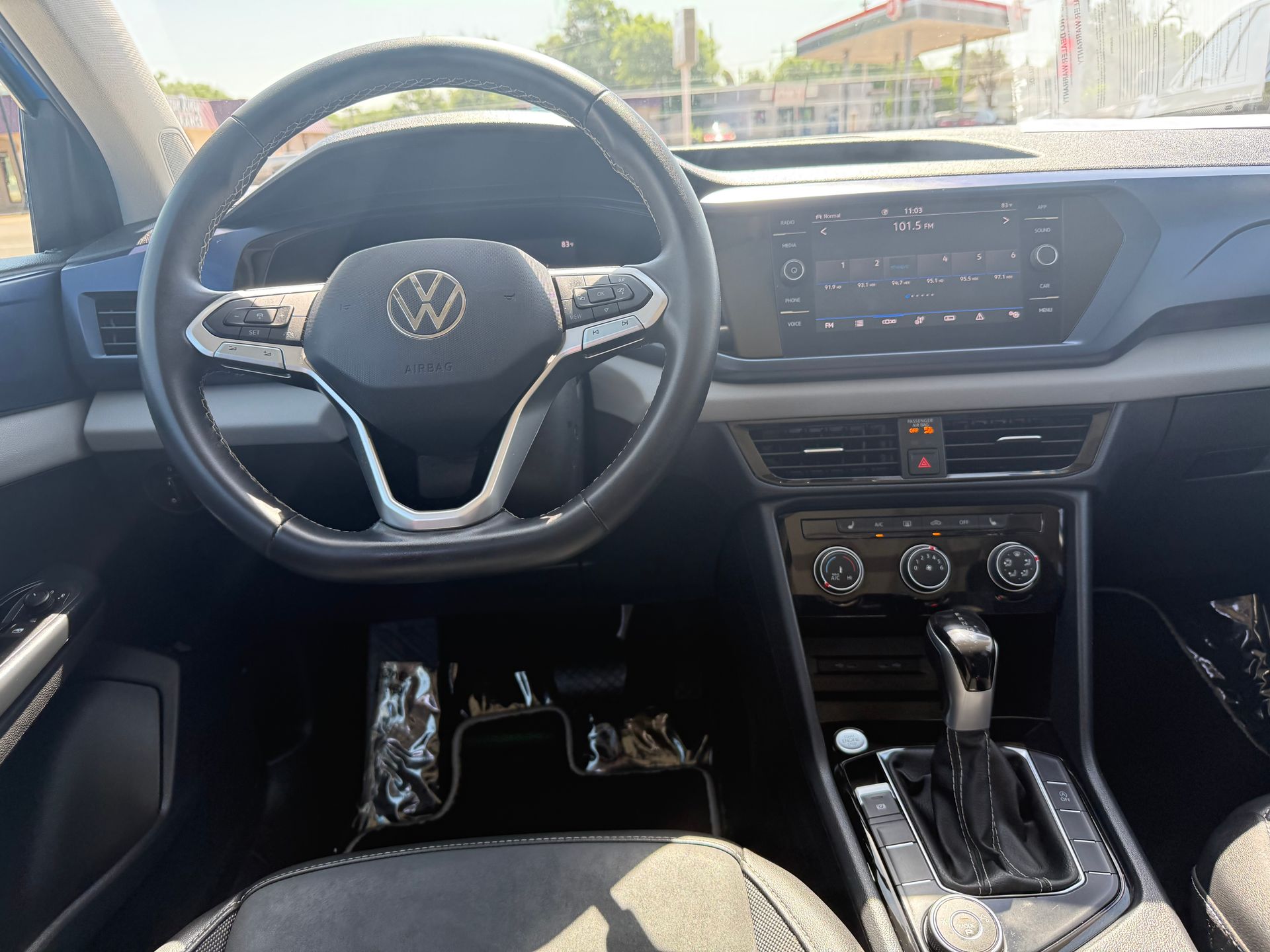 Interior view of a Volkswagen car dashboard with steering wheel, infotainment screen, and gear shift.