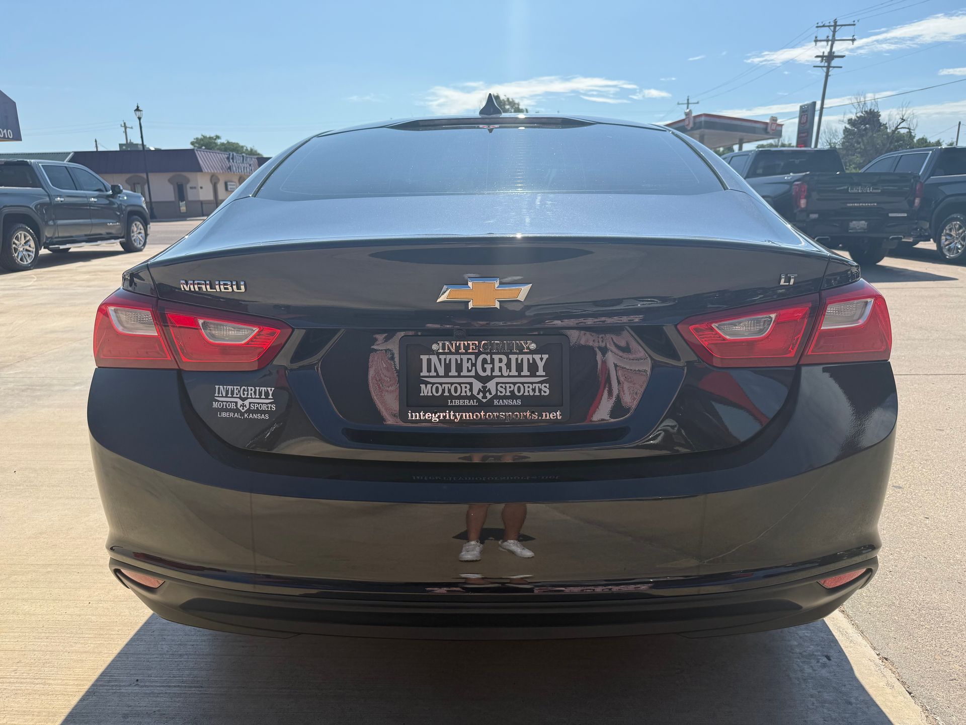 Black Chevrolet Malibu sedan in a dealership lot on a sunny day.