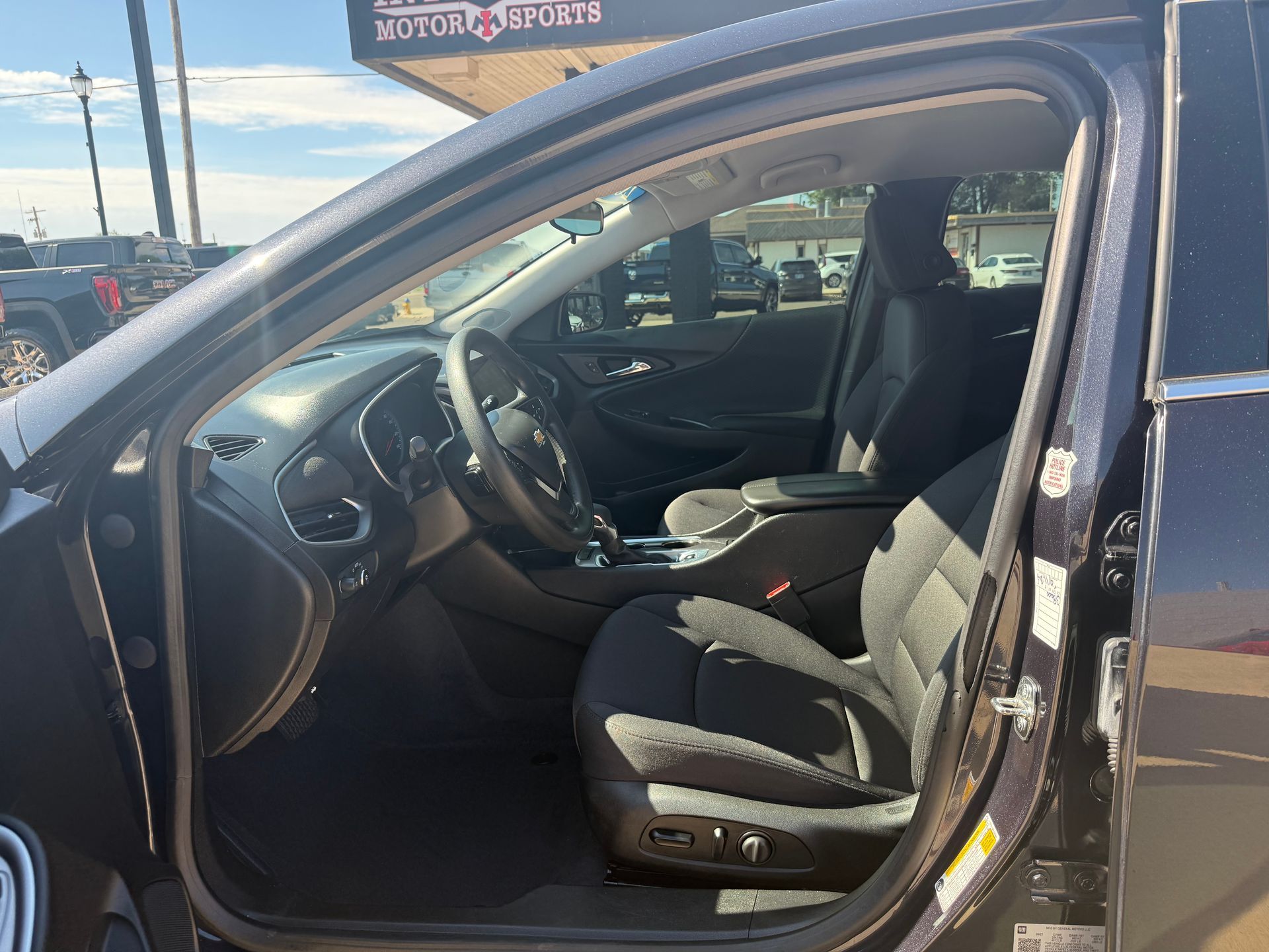 Interior view of a black car with open driver's side door. Seats and dashboard are visible.