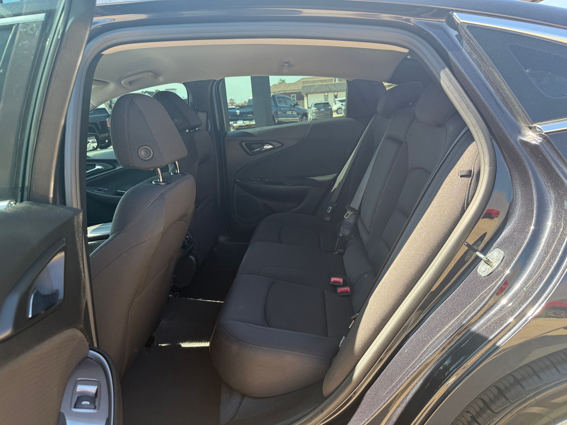 Interior rear view of a dark-colored car; the back seat and a front seat are visible.