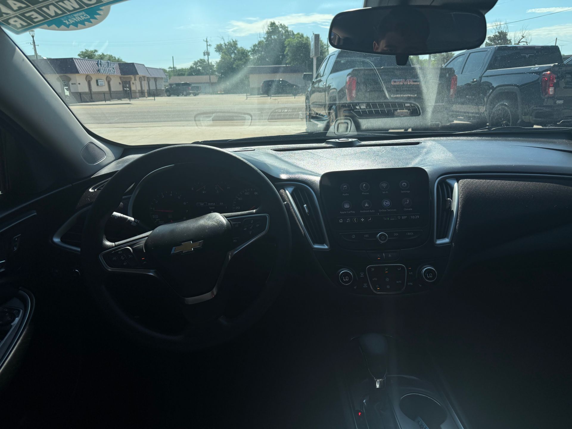 Interior of a car, showcasing the steering wheel, dashboard, and windshield with a view of the outside.