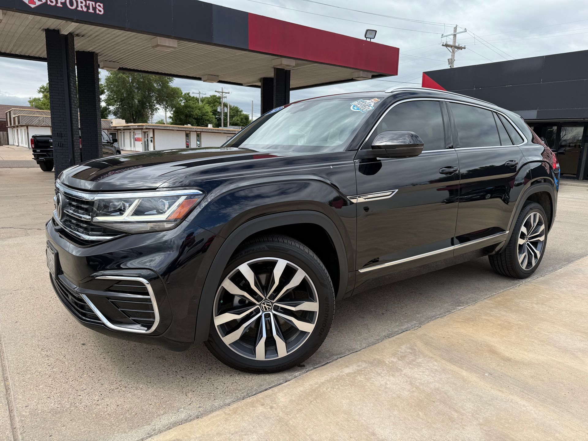 Gray Dodge Durango SUV parked outside a dealership with a red and white sign.
