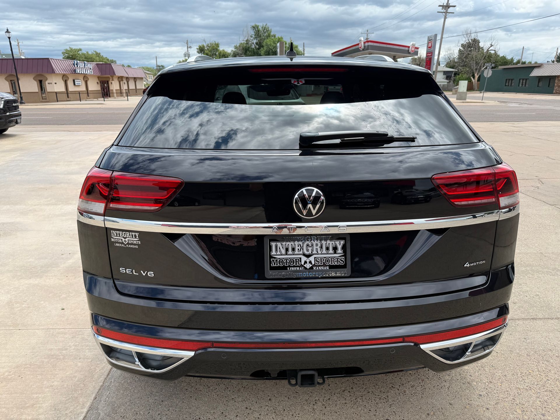 Black Volkswagen Atlas SUV, rear view, chrome trim, dealership setting.