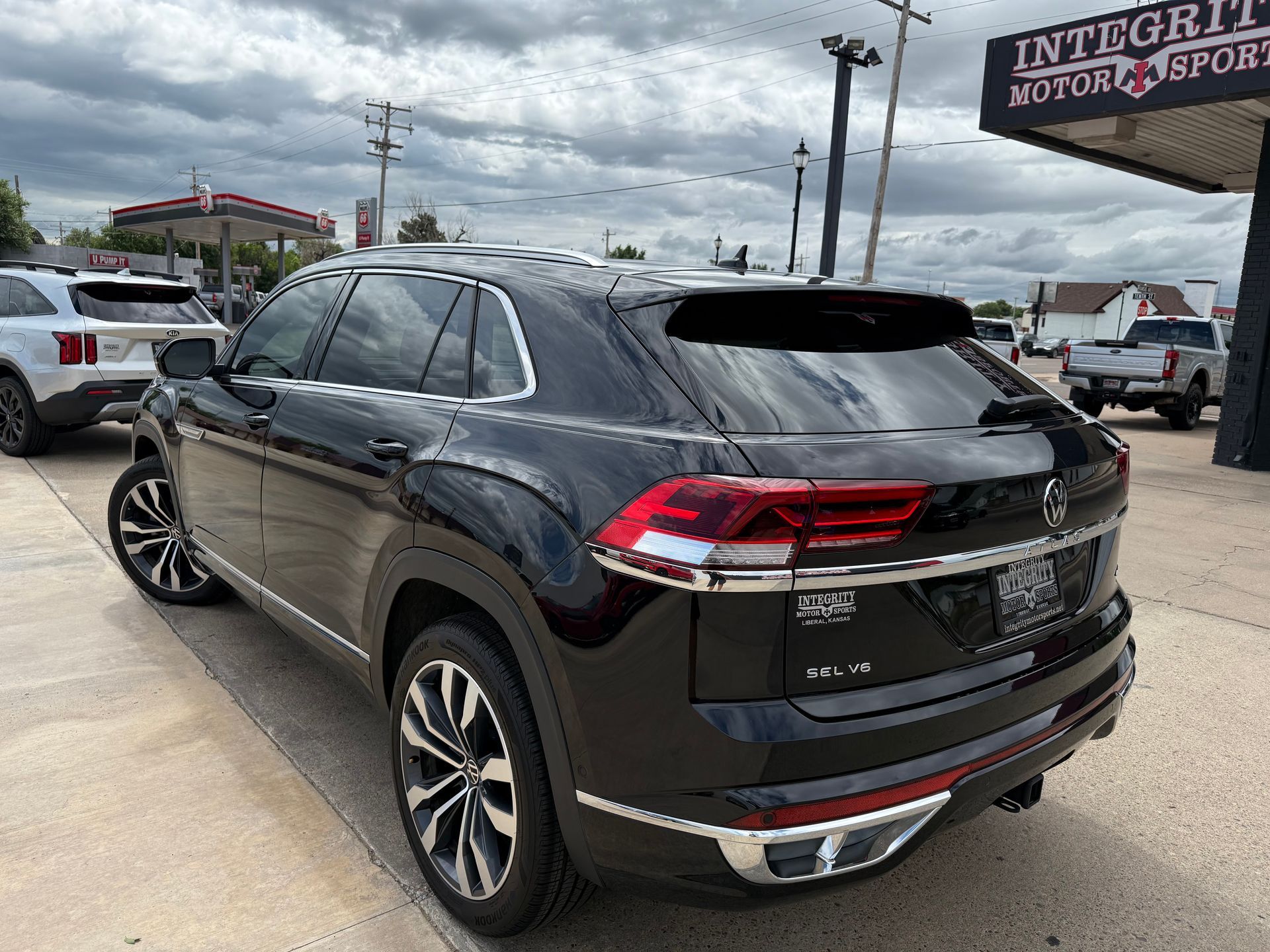 Black VW Atlas SUV parked outside a car dealership on a cloudy day.