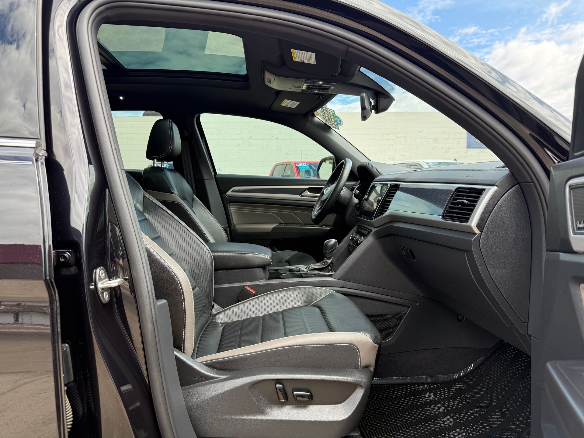 Interior view of a black SUV with black and white seats, sunroof, and dashboard visible.