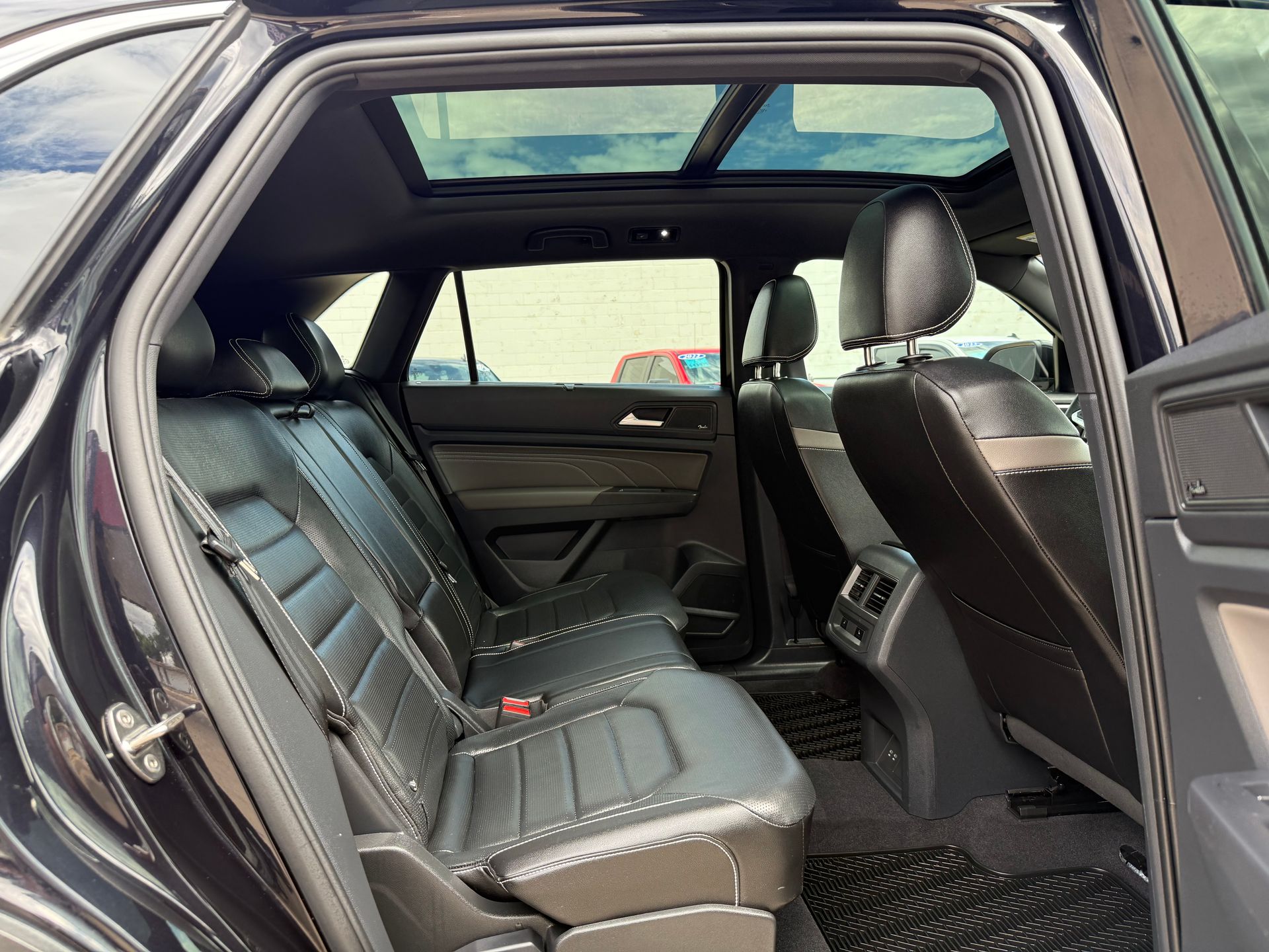 Interior view of a black SUV with leather seats, open sunroof, and black floor mats.