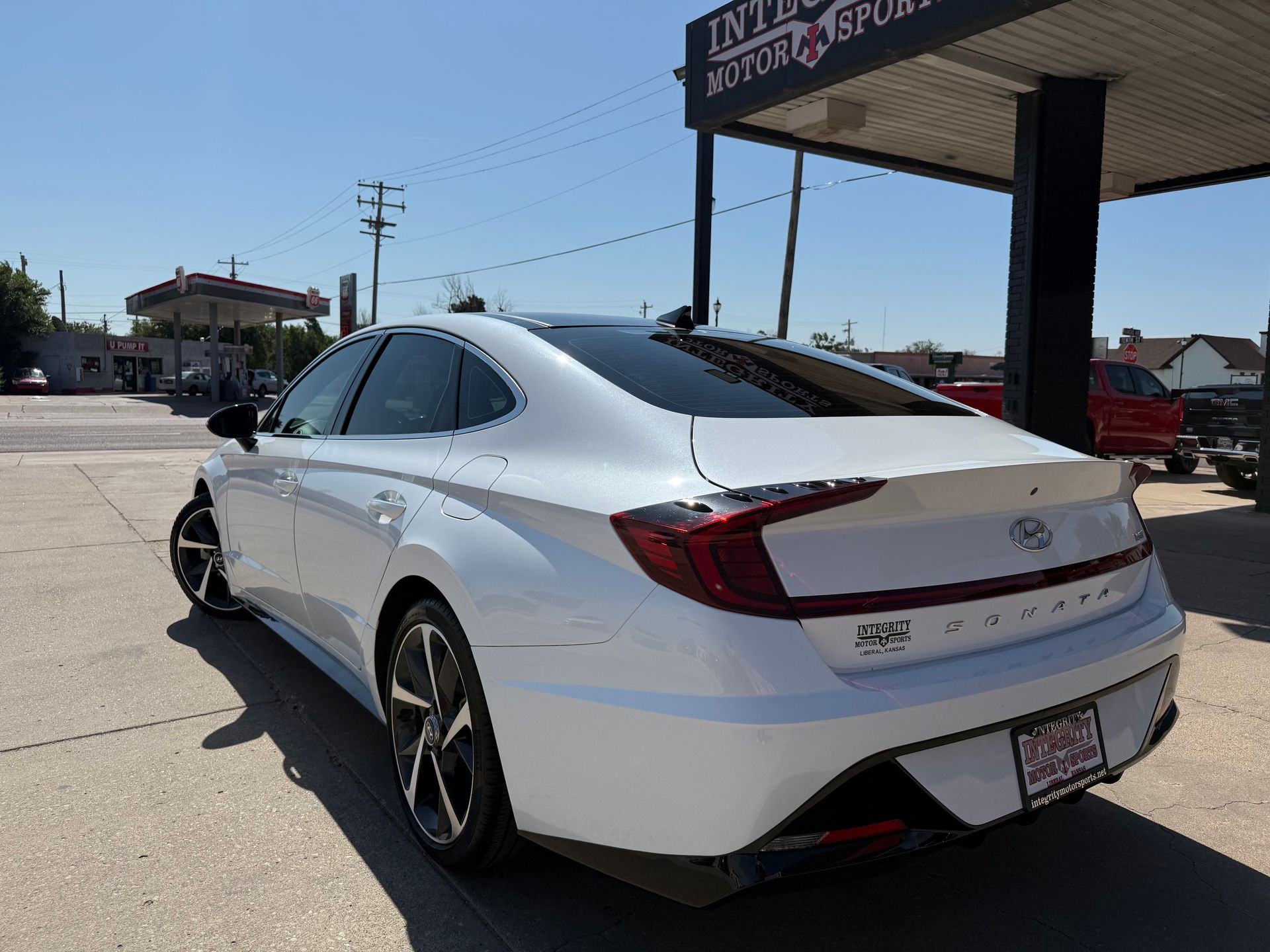 White Hyundai Sonata parked outside a dealership on a sunny day.