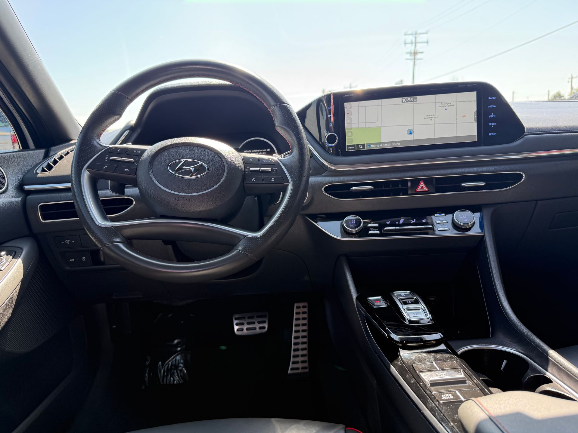 Interior view of a car dashboard, black and silver, with a steering wheel and a navigation screen.