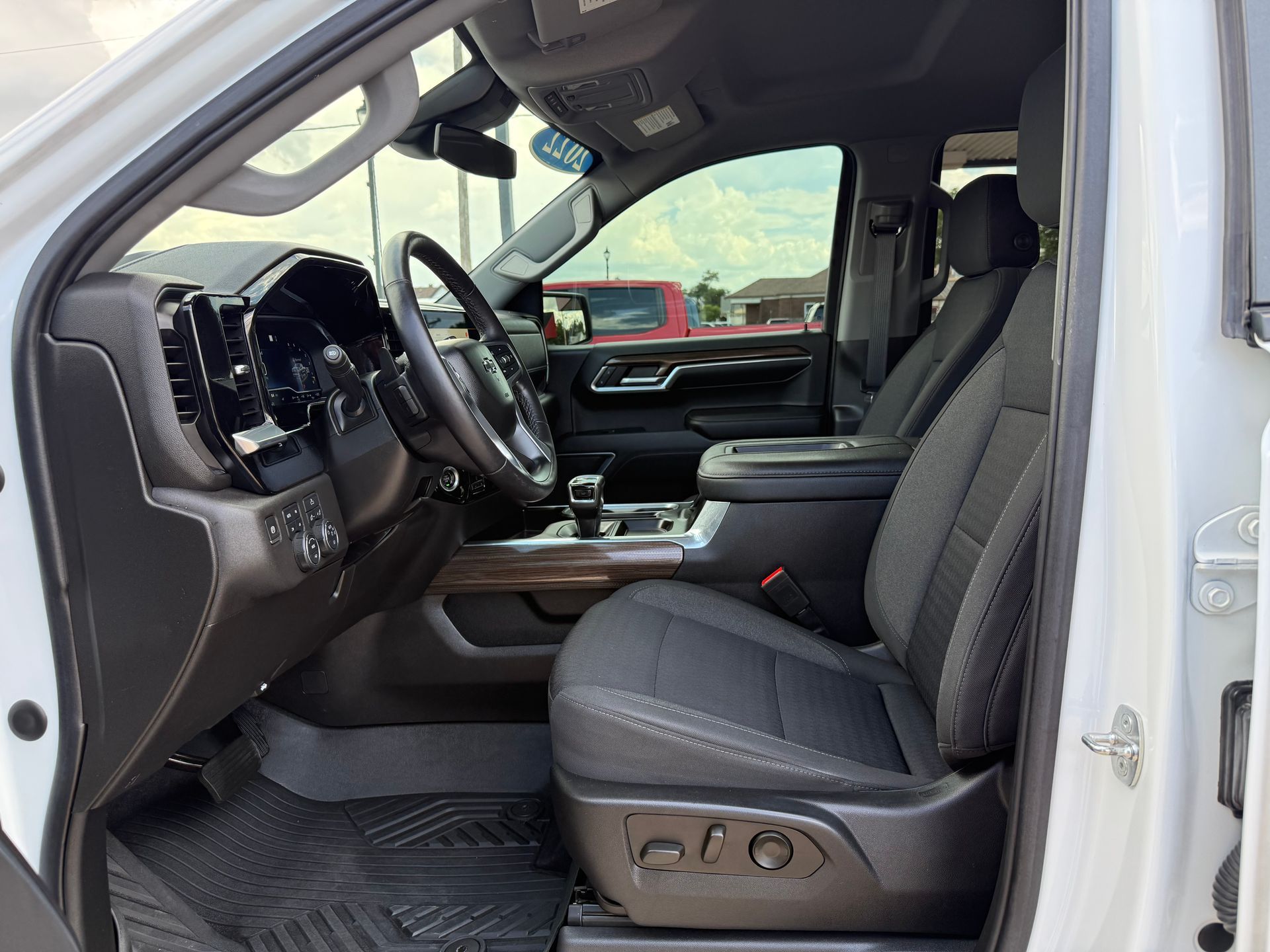 Interior view of a white truck, showing black driver's seat, dashboard, steering wheel, and center console.