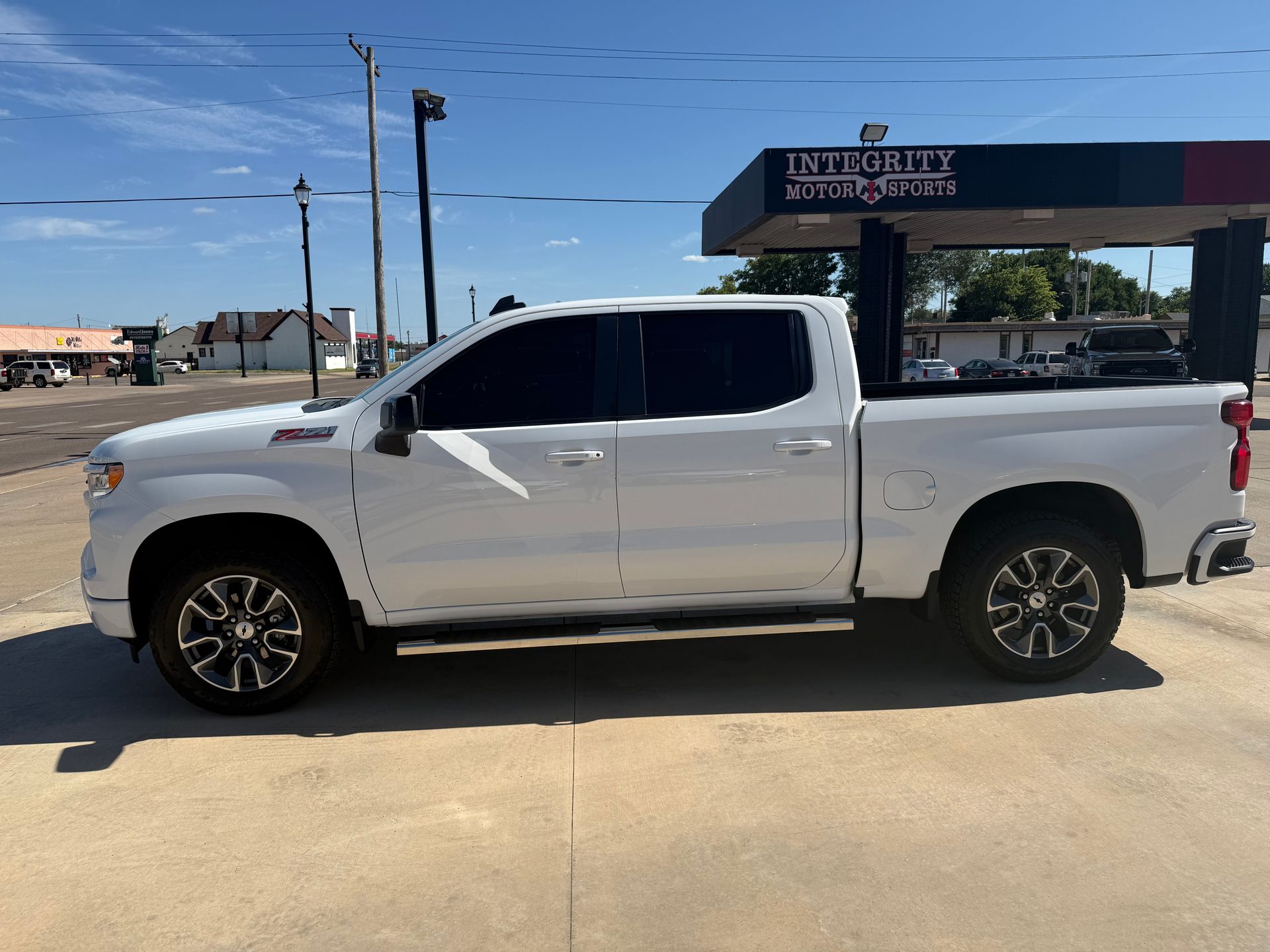 White pickup truck parked outside a gas station on a sunny day.